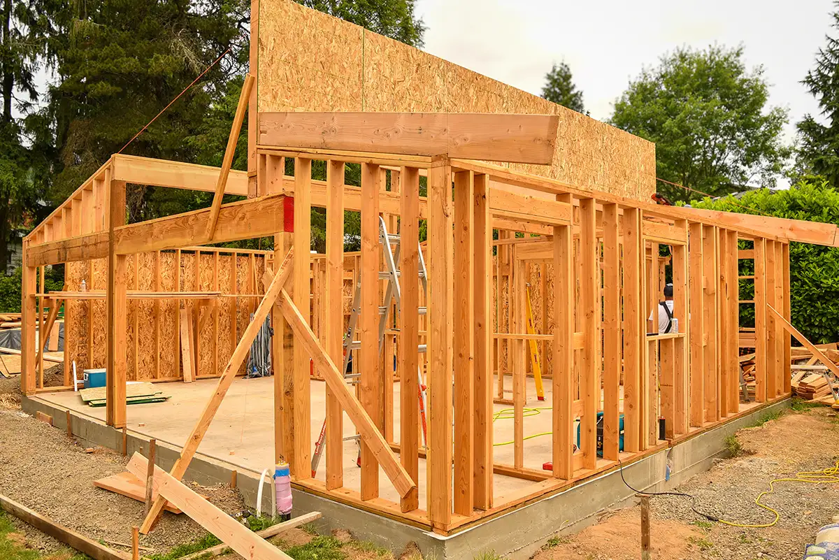 Wooden frame structure of an ADU under construction on a concrete foundation in an outdoor setting.