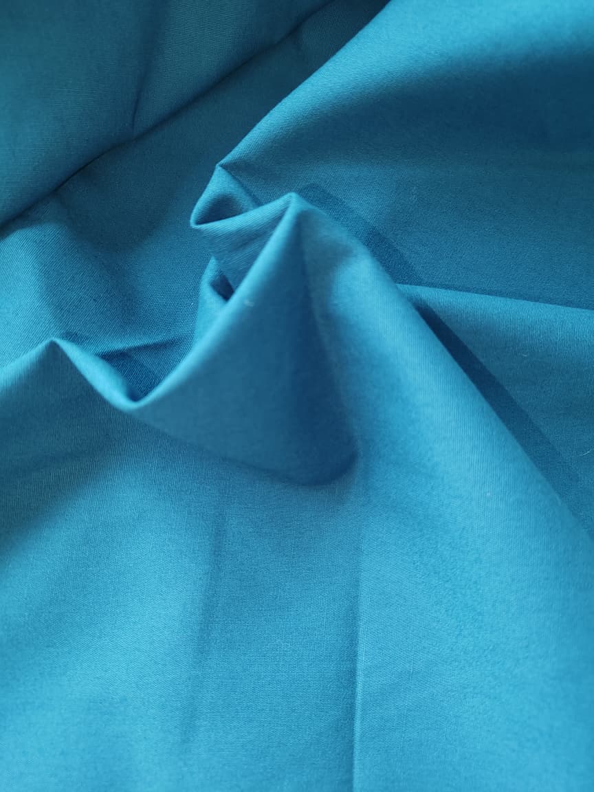 Close-up of soft, wrinkled pink cotton fabric displaying fine weave texture.