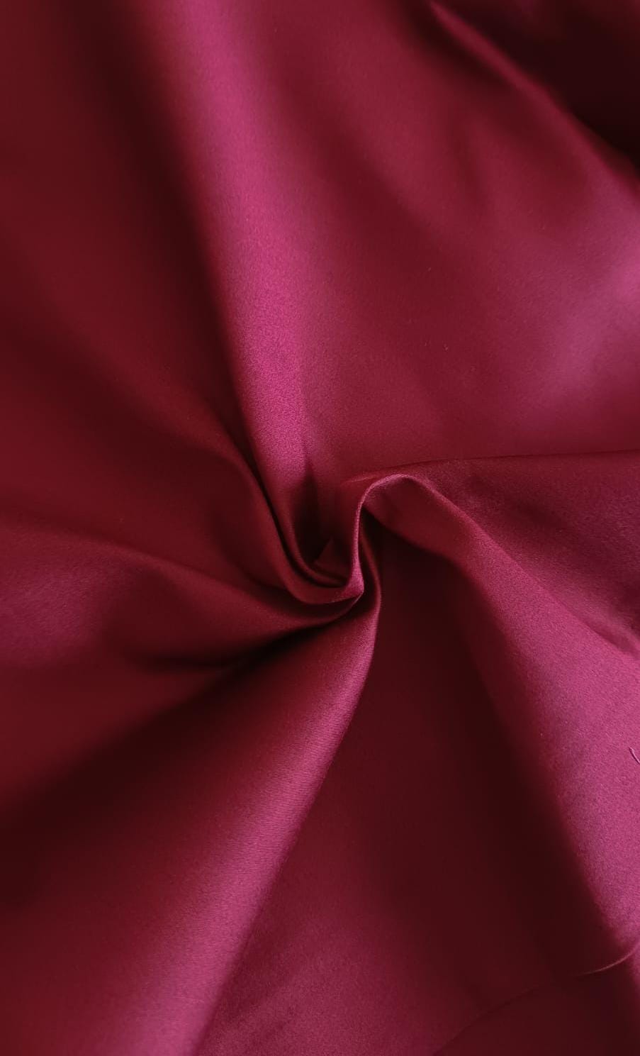 Close-up of soft, wrinkled pink cotton fabric displaying fine weave texture.
