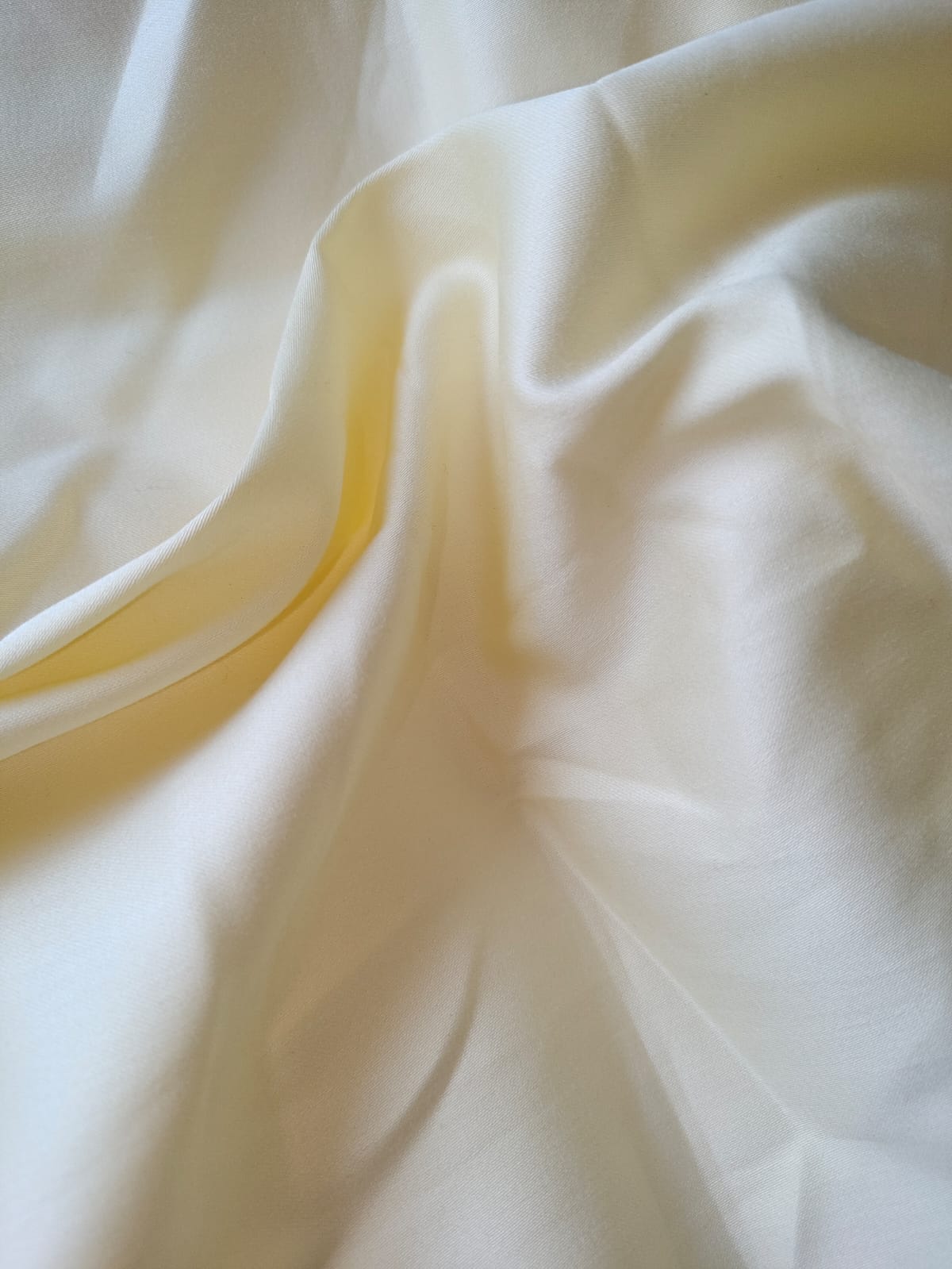 Close-up of soft, wrinkled pink cotton fabric displaying fine weave texture.