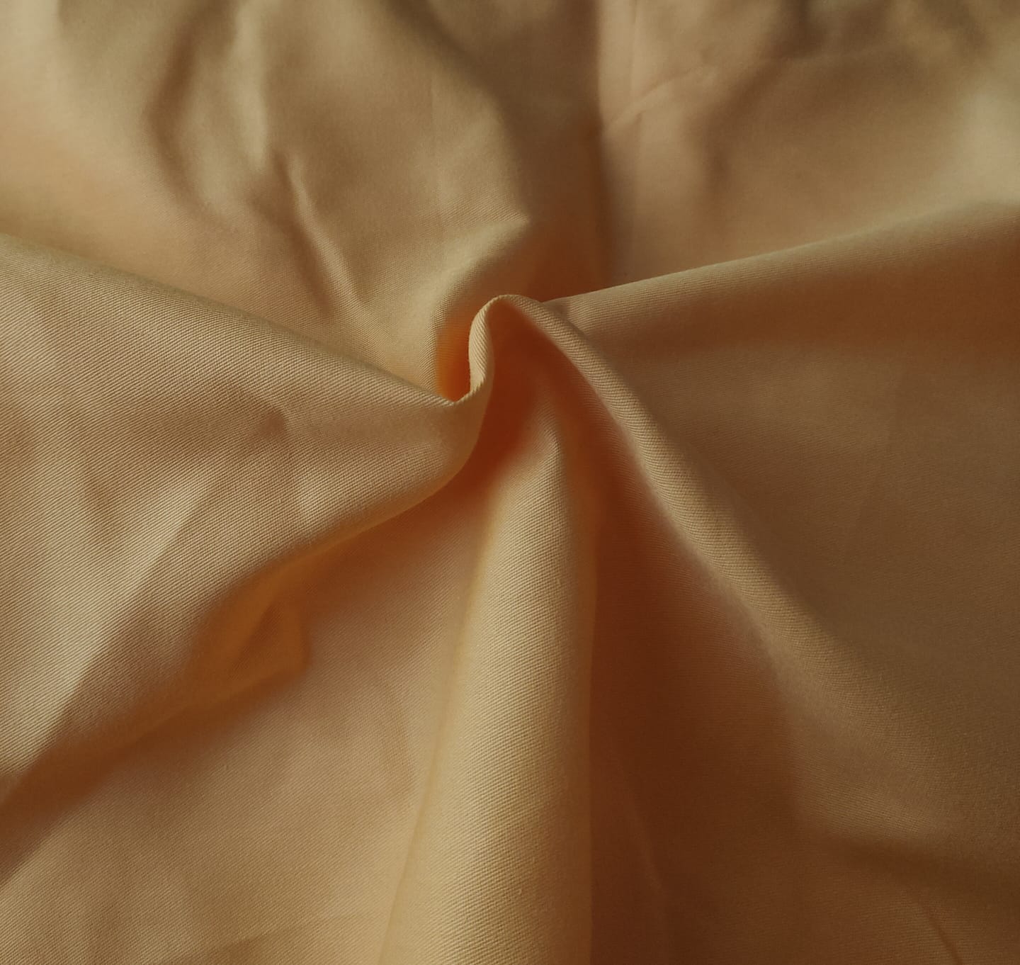 Close-up of soft, wrinkled pink cotton fabric displaying fine weave texture.