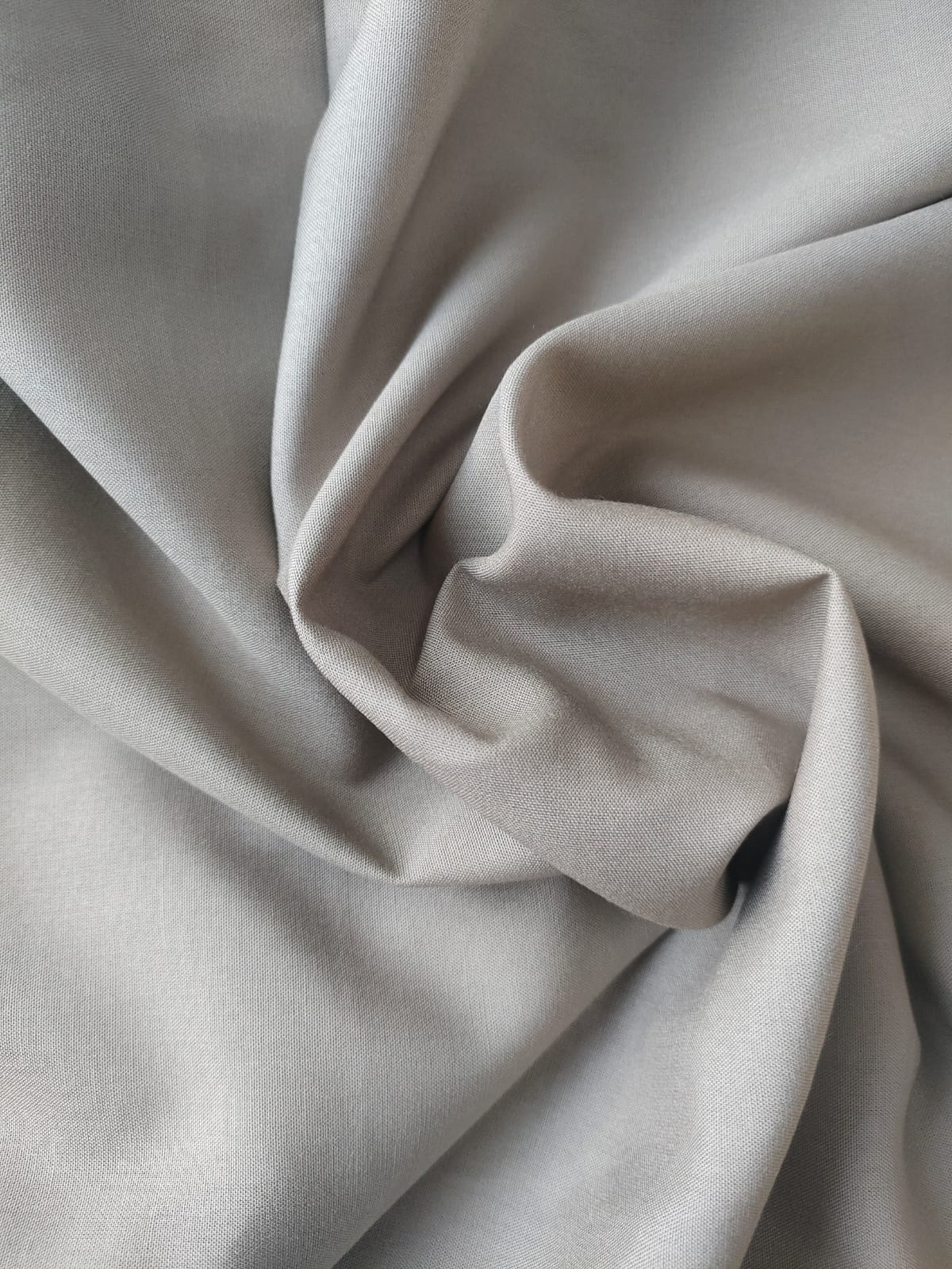 Close-up of soft, wrinkled pink cotton fabric displaying fine weave texture.