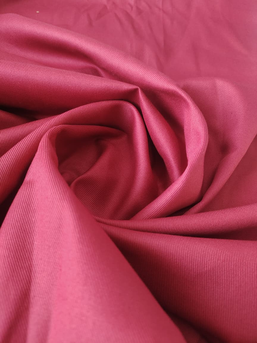 Close-up of soft, wrinkled pink cotton fabric displaying fine weave texture.