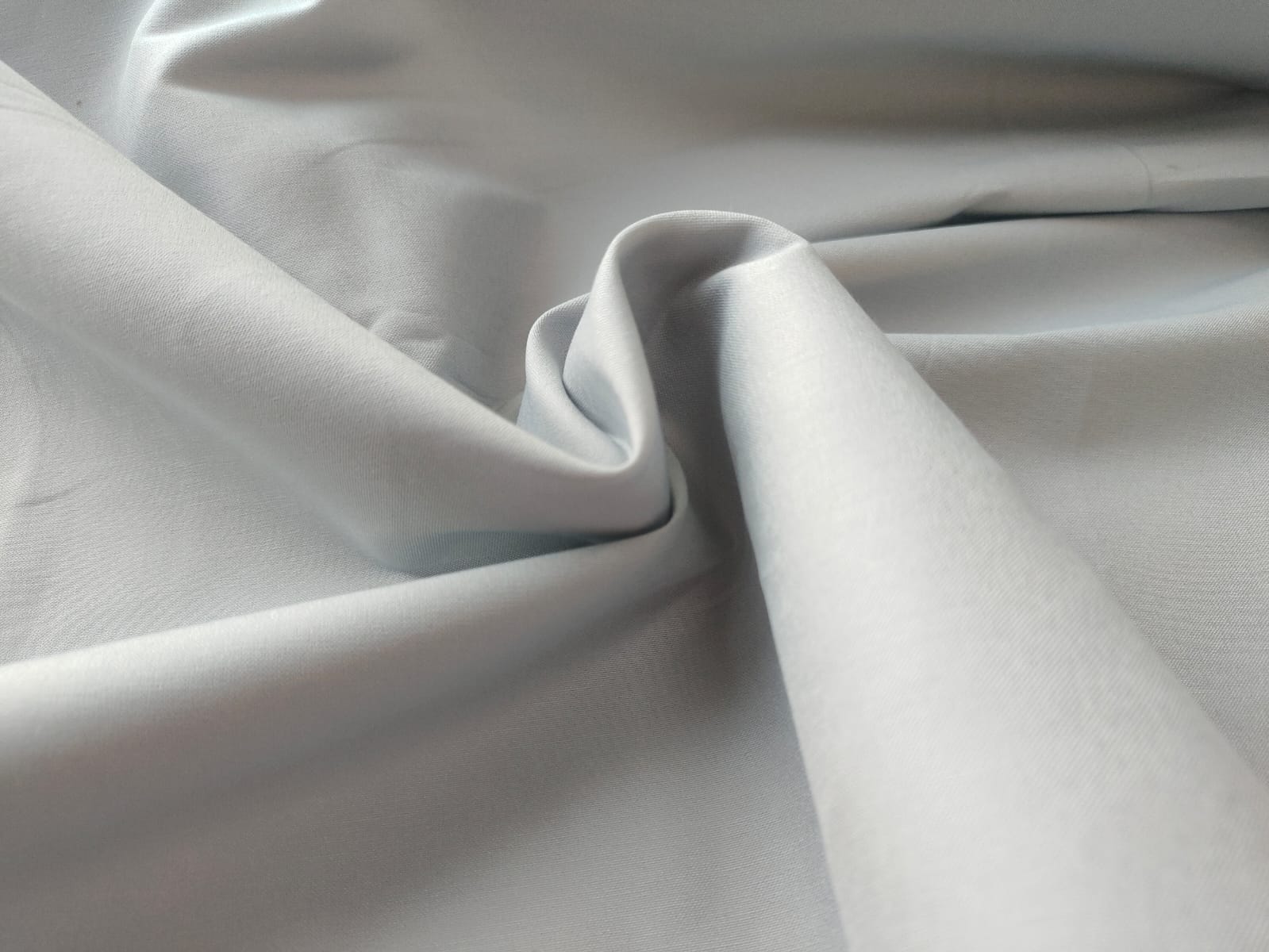 Close-up of soft, wrinkled pink cotton fabric displaying fine weave texture.