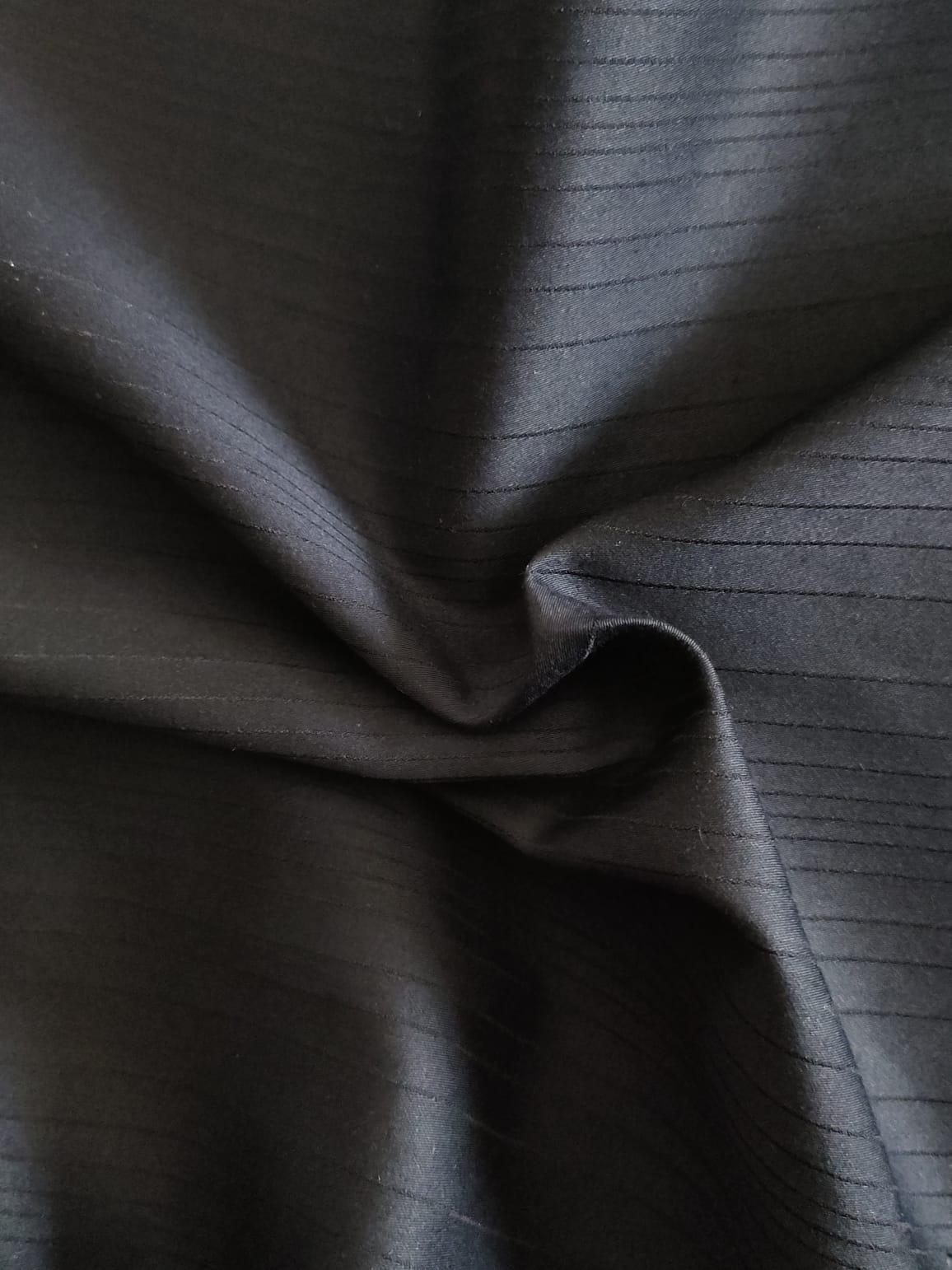 Close-up of soft, wrinkled pink cotton fabric displaying fine weave texture.
