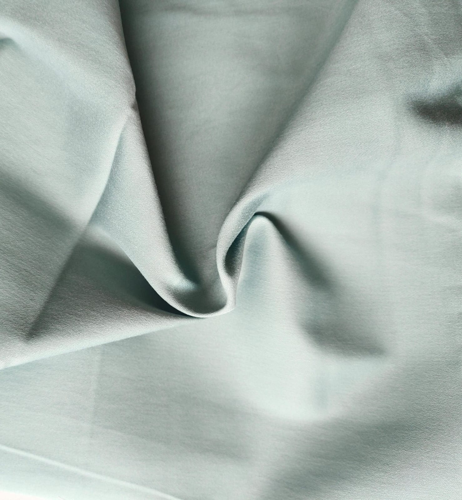 Close-up of soft, wrinkled pink cotton fabric displaying fine weave texture.