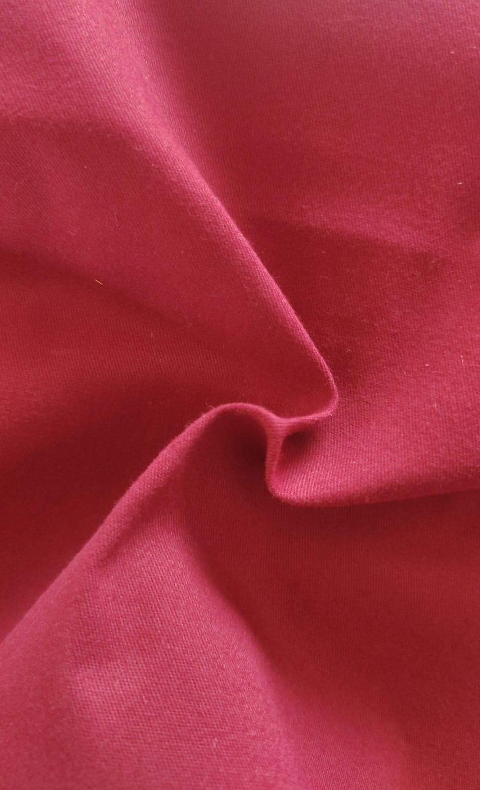 Close-up of soft, wrinkled pink cotton fabric displaying fine weave texture.