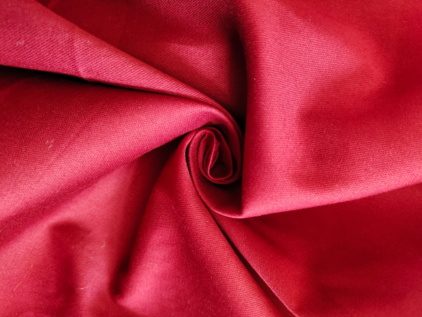 Close-up of soft, wrinkled pink cotton fabric displaying fine weave texture.