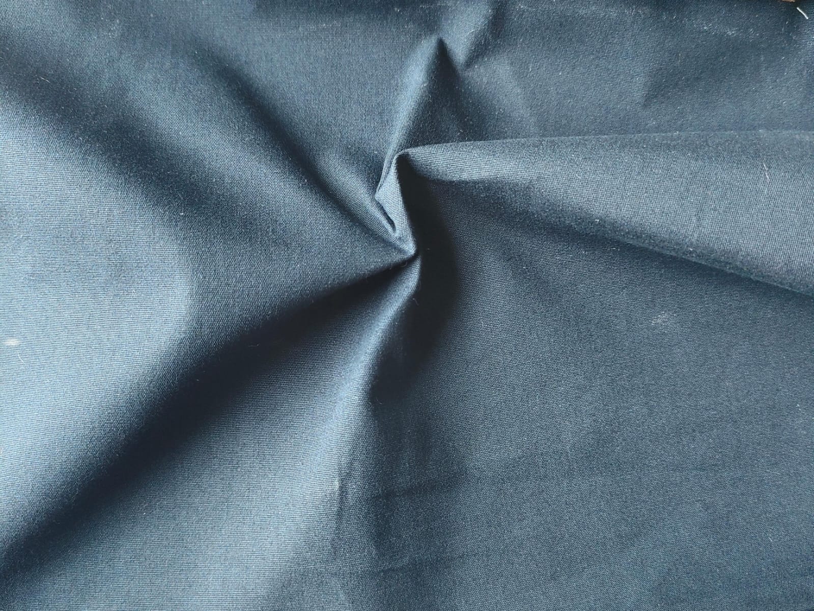 Close-up of soft, wrinkled pink cotton fabric displaying fine weave texture.