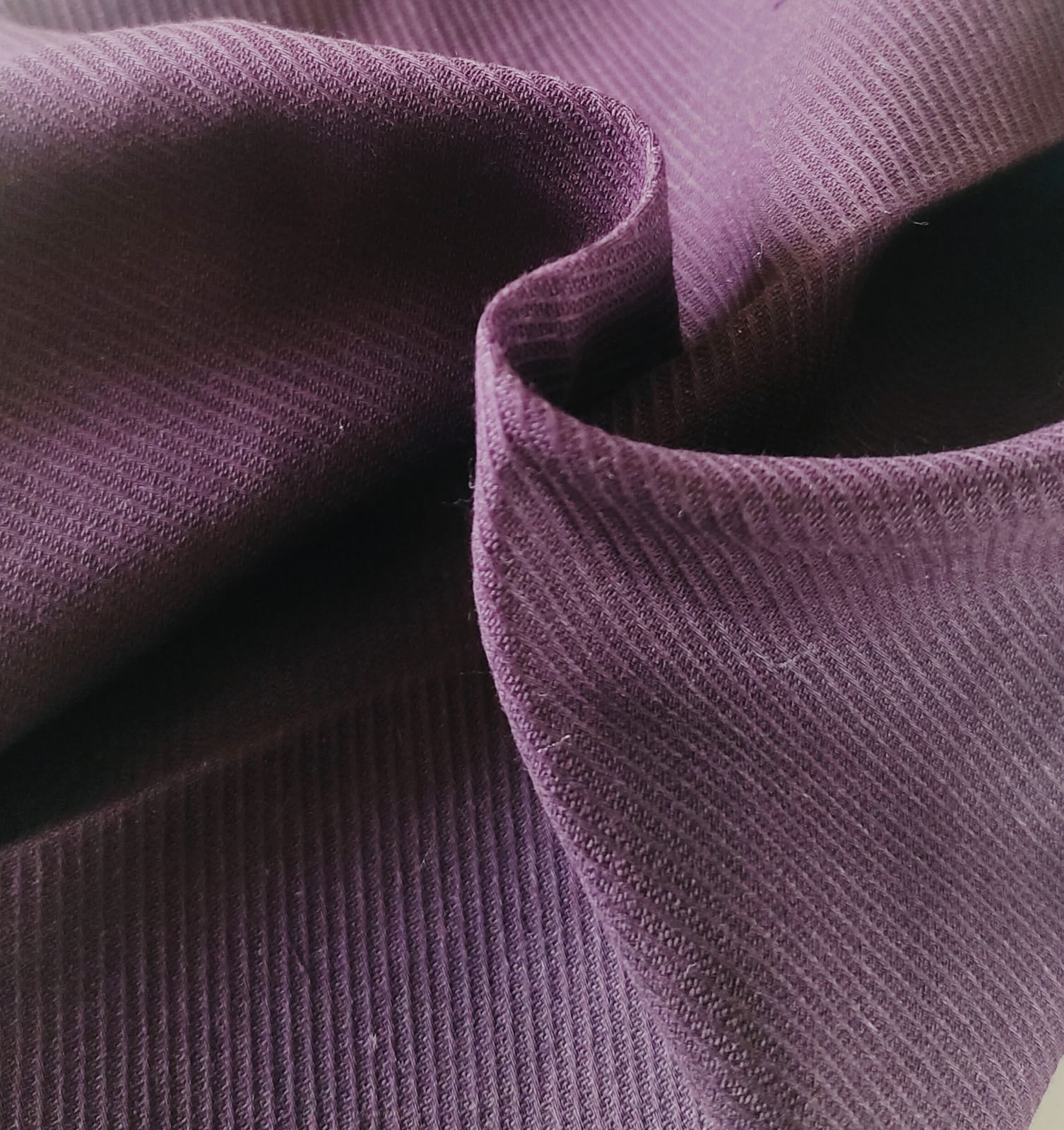 Close-up of soft, wrinkled pink cotton fabric displaying fine weave texture.