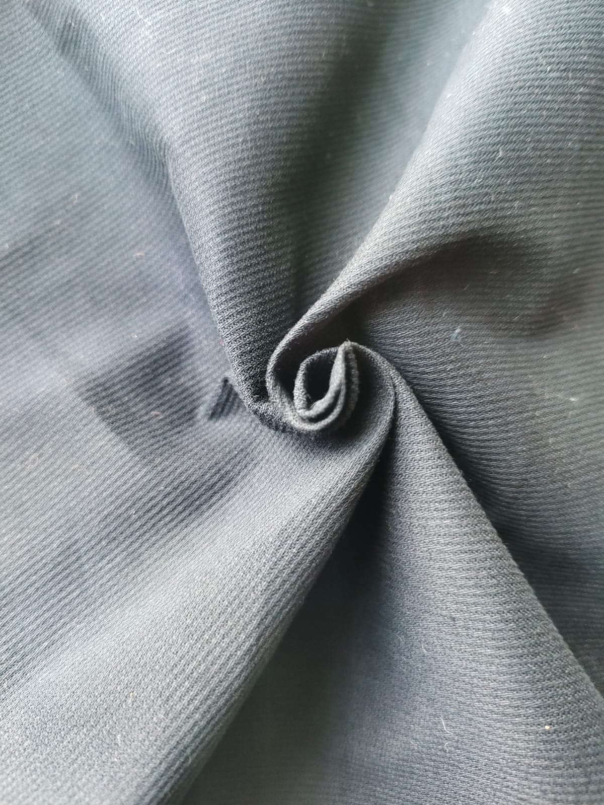 Close-up of soft, wrinkled pink cotton fabric displaying fine weave texture.