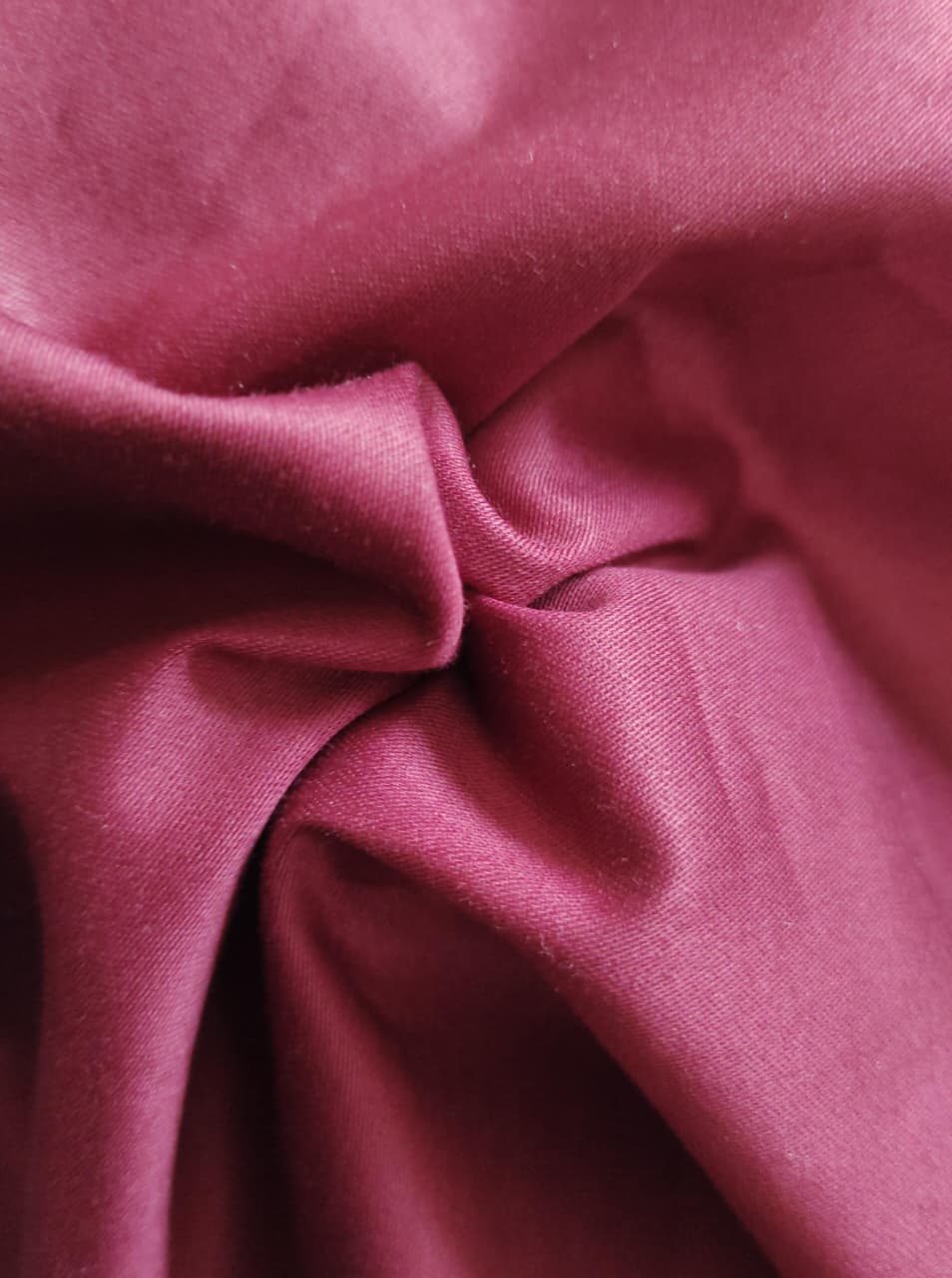 Close-up of soft, wrinkled pink cotton fabric displaying fine weave texture.