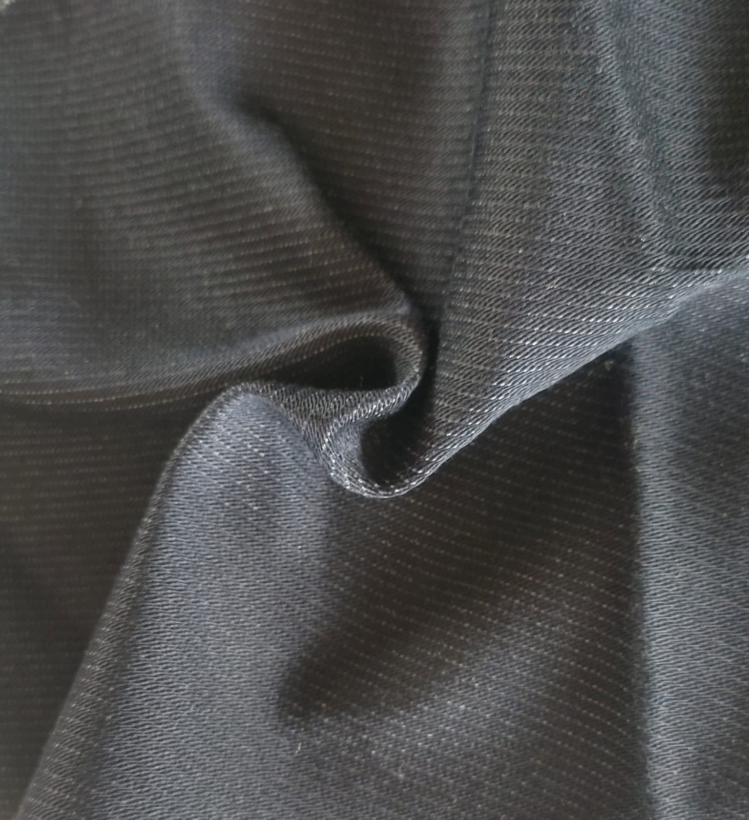 Close-up of soft, wrinkled pink cotton fabric displaying fine weave texture.