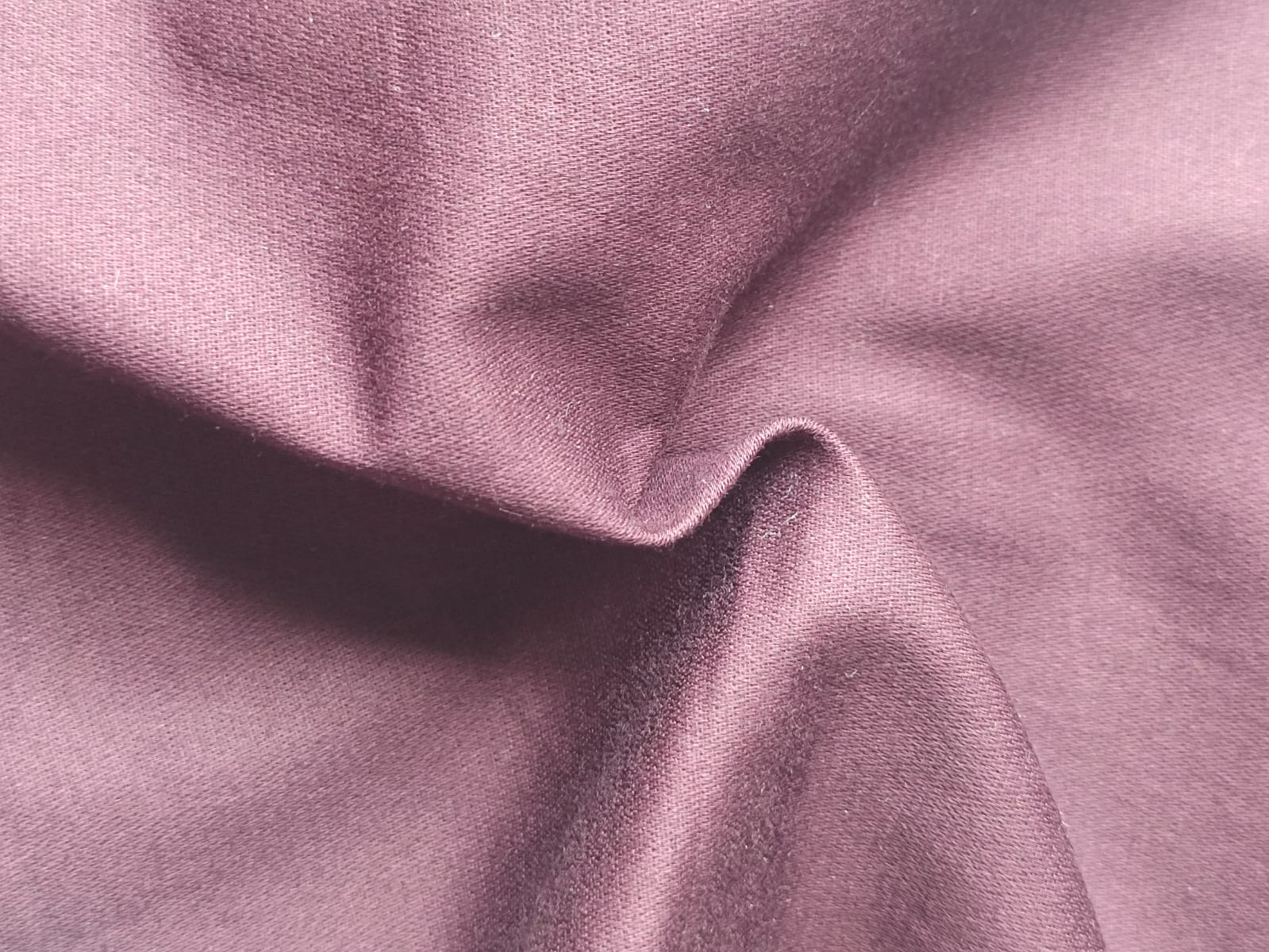 Close-up of soft, wrinkled pink cotton fabric displaying fine weave texture.