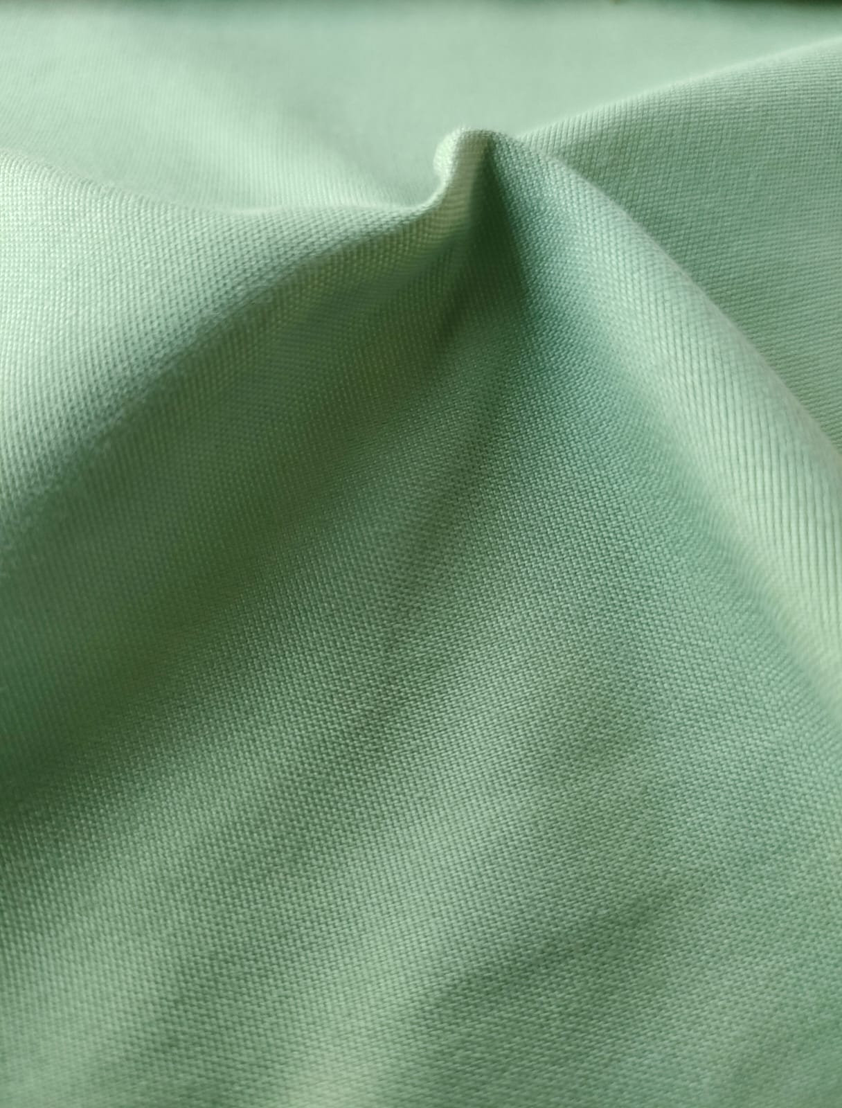 Close-up of soft, wrinkled pink cotton fabric displaying fine weave texture.
