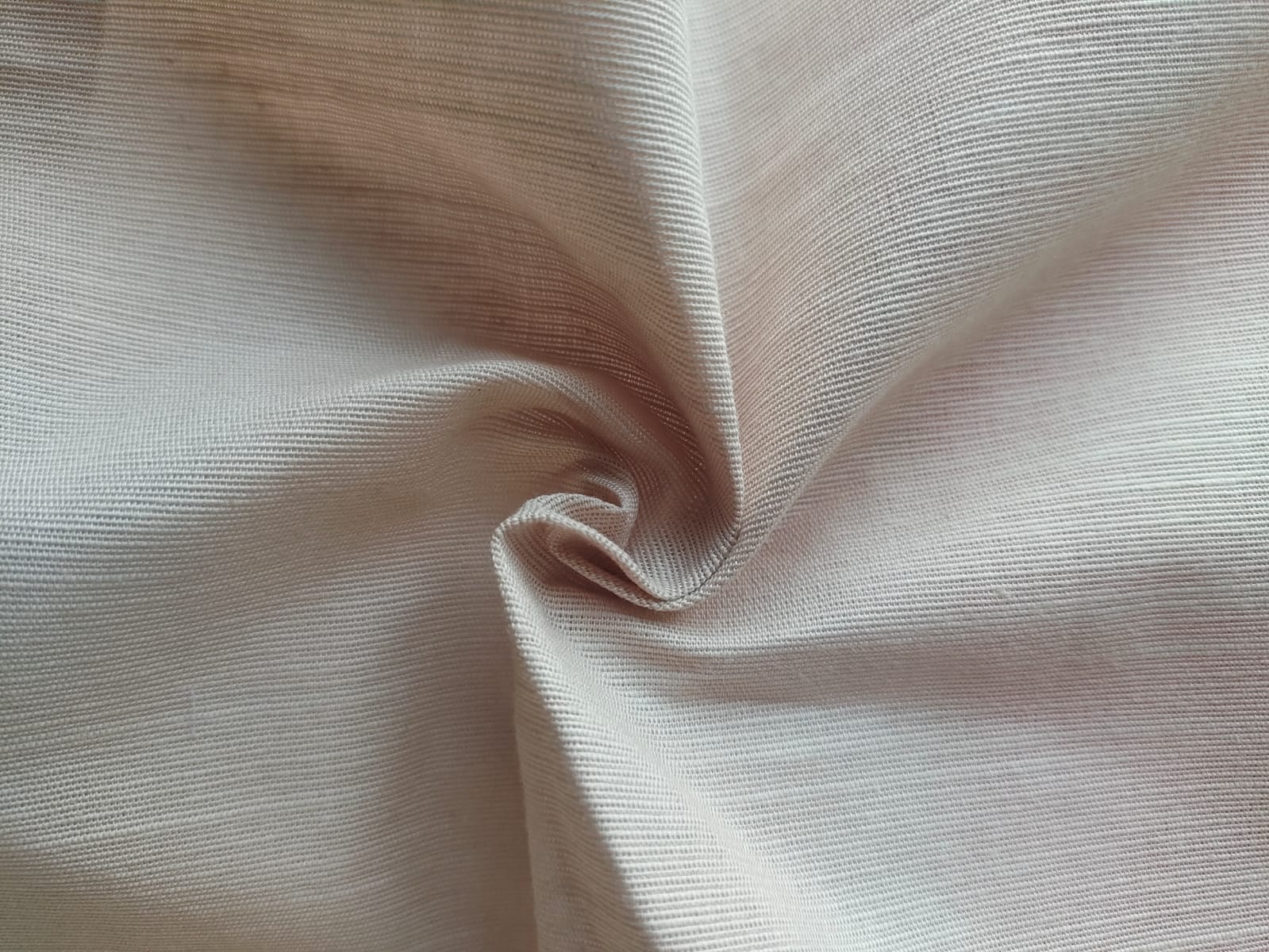 Close-up of soft, wrinkled pink cotton fabric displaying fine weave texture.