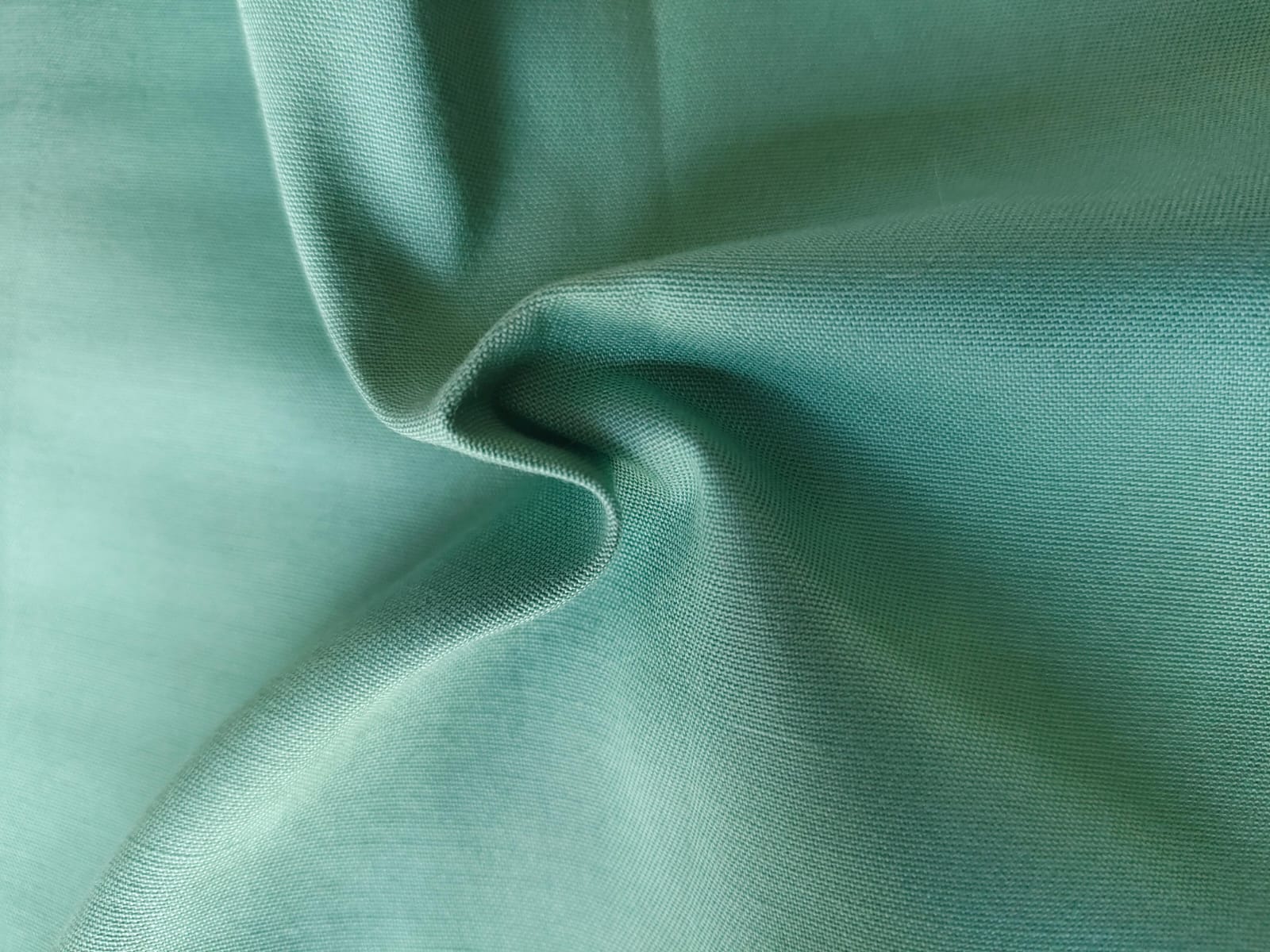 Close-up of soft, wrinkled pink cotton fabric displaying fine weave texture.