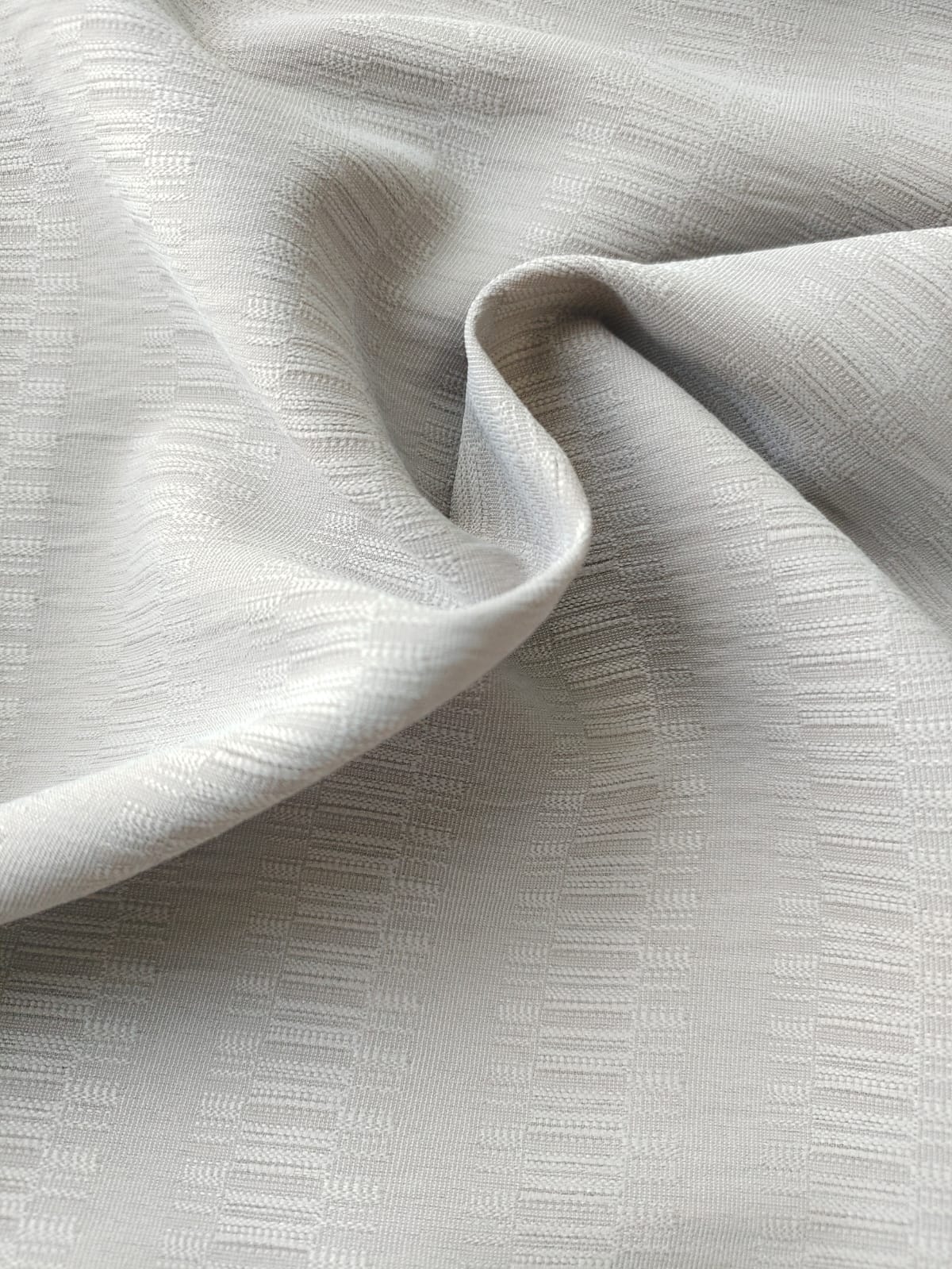 Close-up of soft, wrinkled pink cotton fabric displaying fine weave texture.