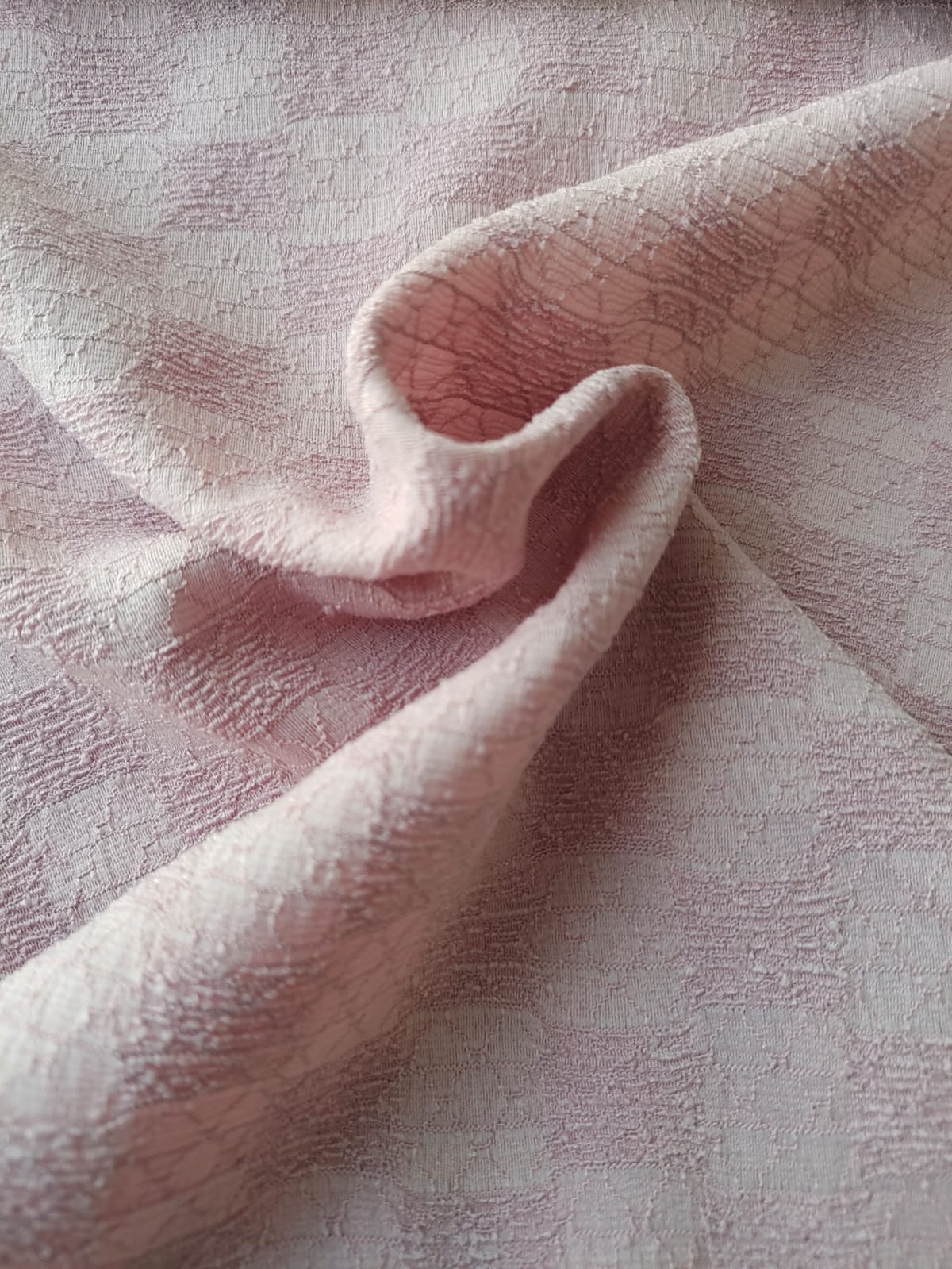 Close-up of soft, wrinkled pink cotton fabric displaying fine weave texture.