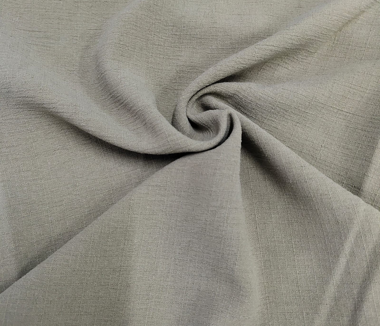 Close-up of soft, wrinkled pink cotton fabric displaying fine weave texture.