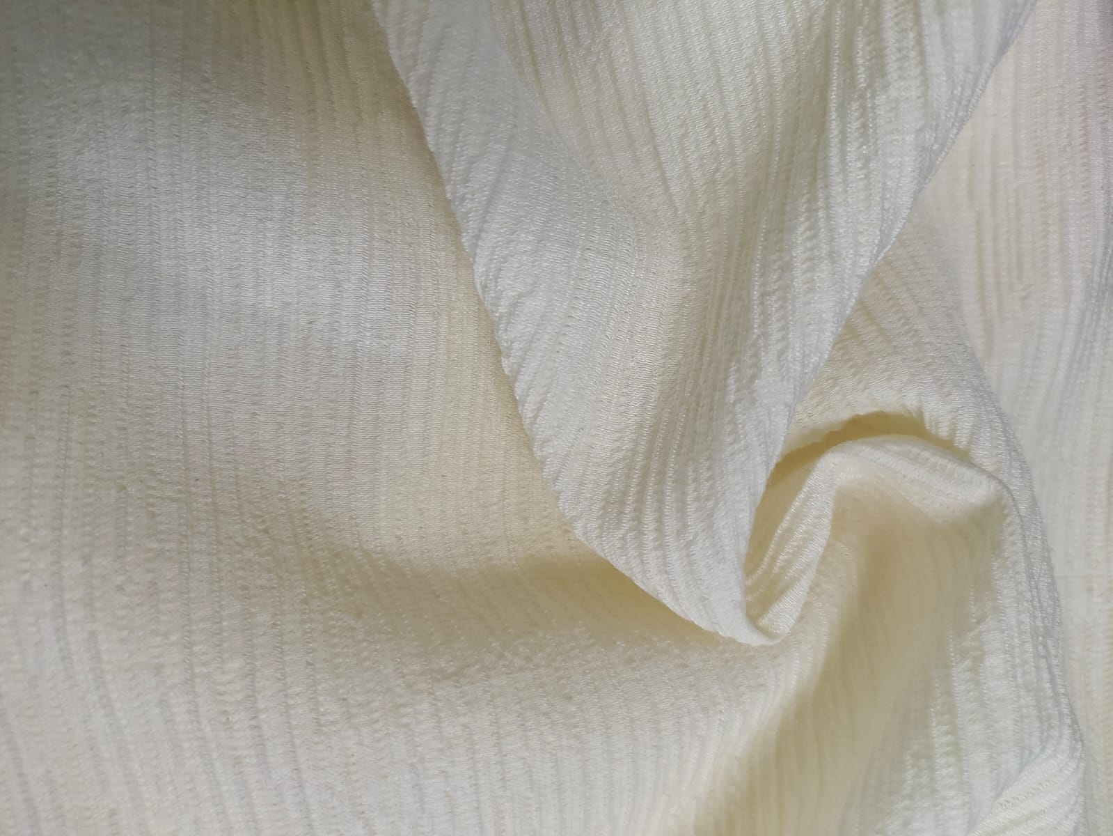 Close-up of soft, wrinkled pink cotton fabric displaying fine weave texture.