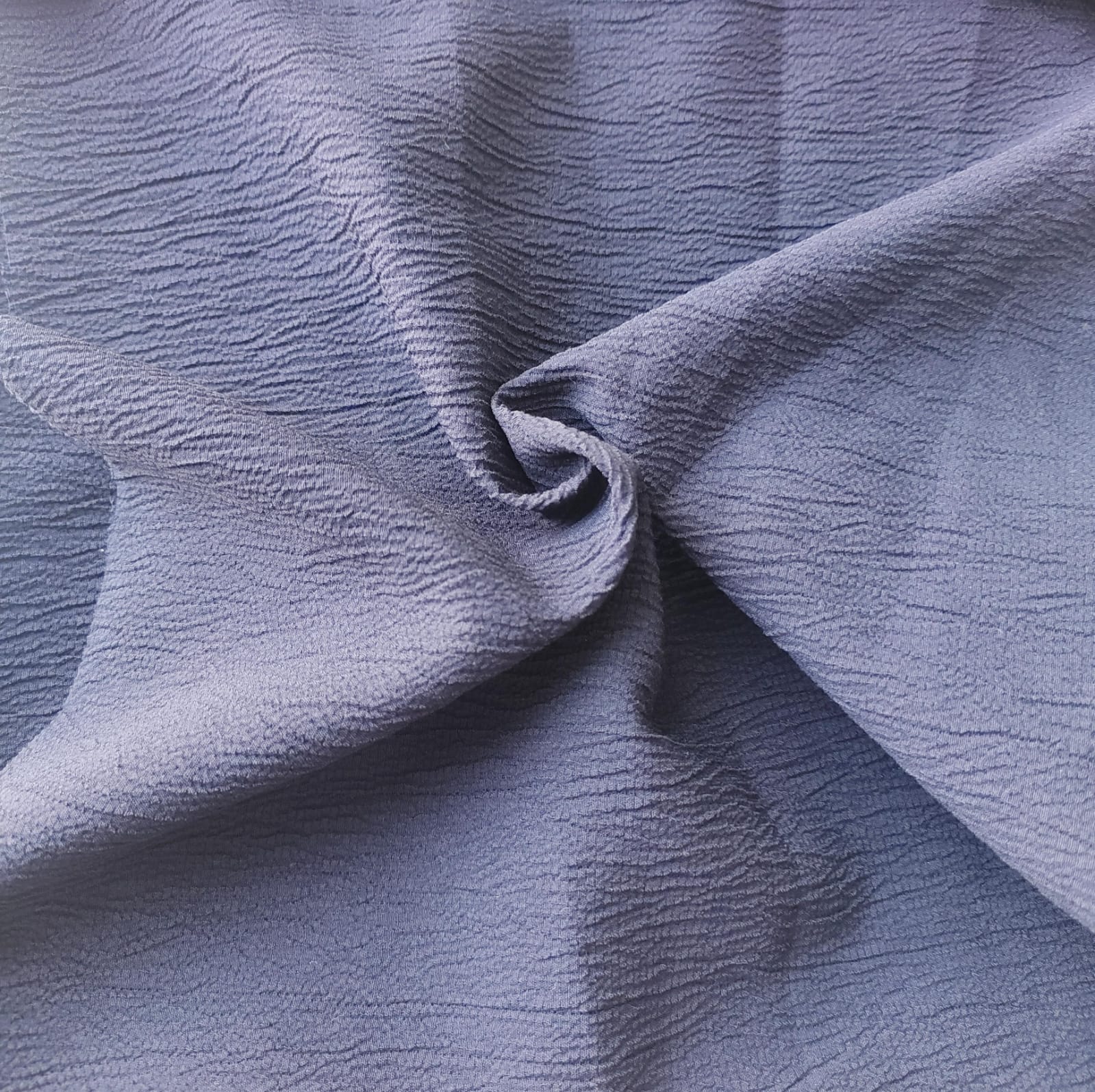 Close-up of soft, wrinkled pink cotton fabric displaying fine weave texture.