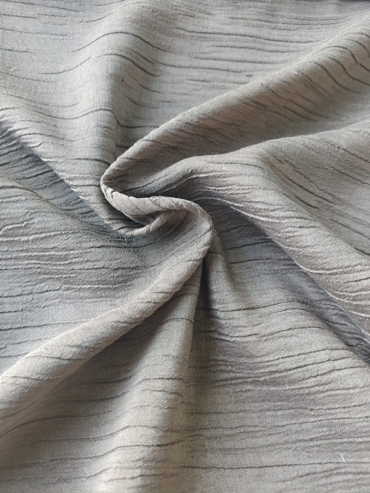 Close-up of soft, wrinkled pink cotton fabric displaying fine weave texture.