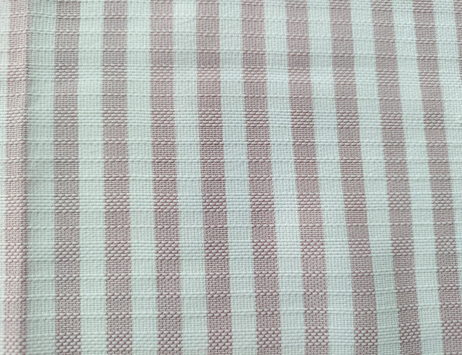 Close-up of soft, wrinkled pink cotton fabric displaying fine weave texture.
