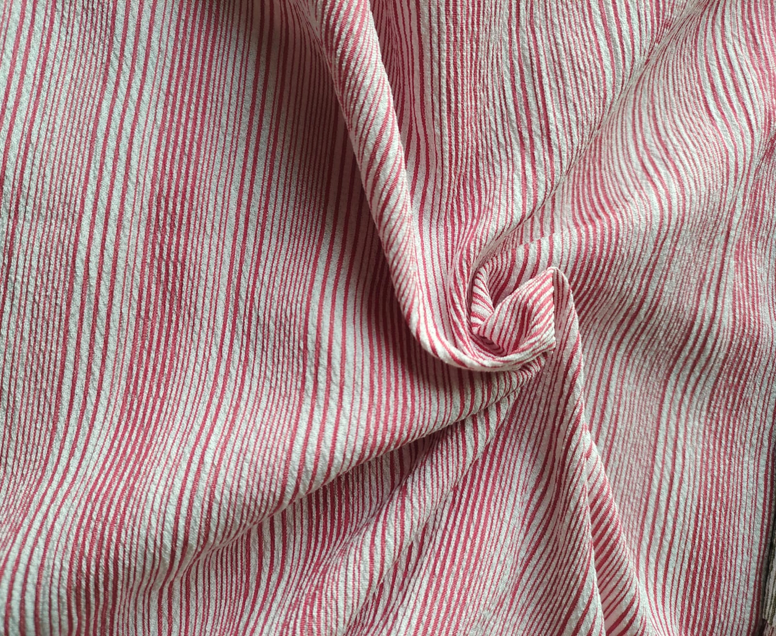 Close-up of soft, wrinkled pink cotton fabric displaying fine weave texture.