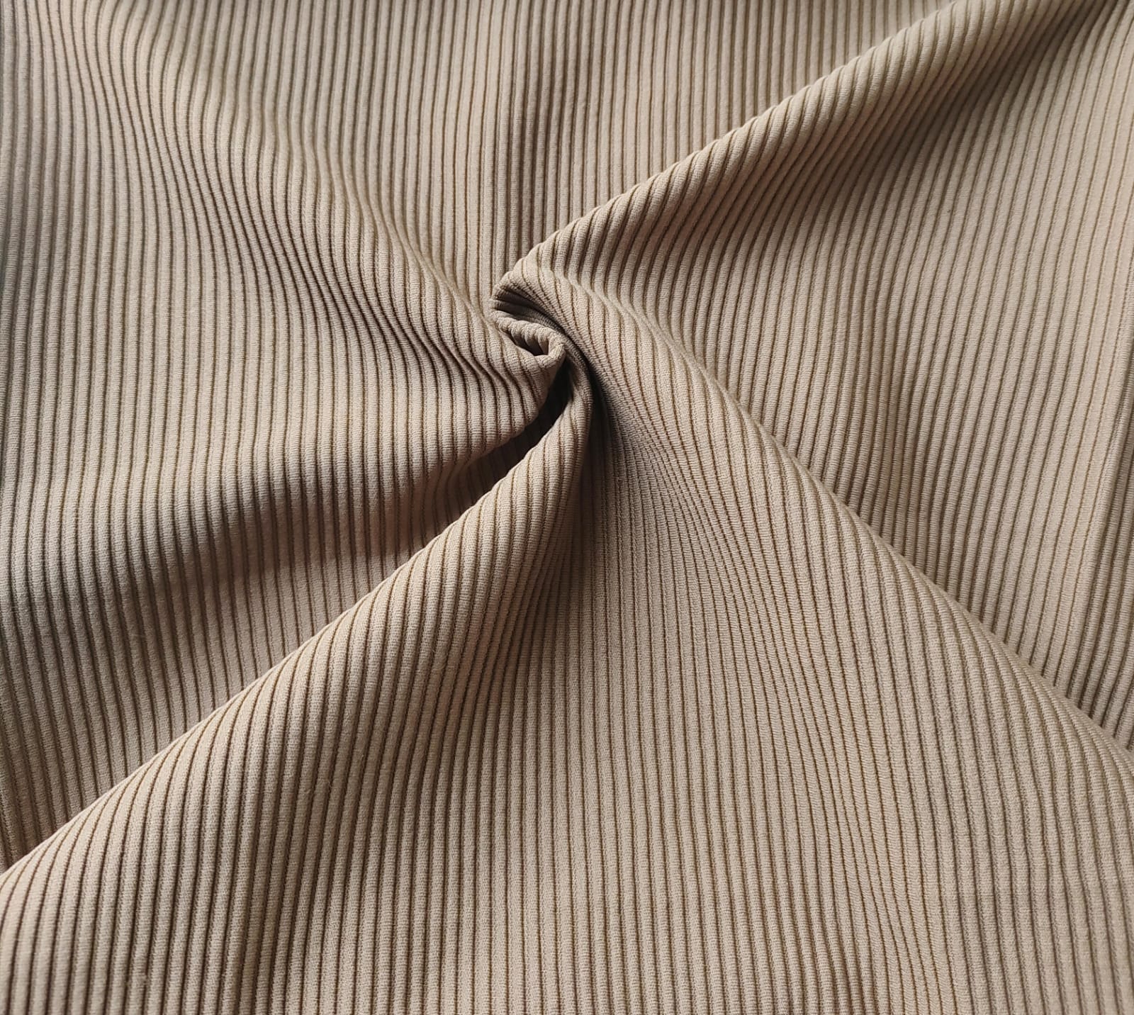 Close-up of soft, wrinkled pink cotton fabric displaying fine weave texture.
