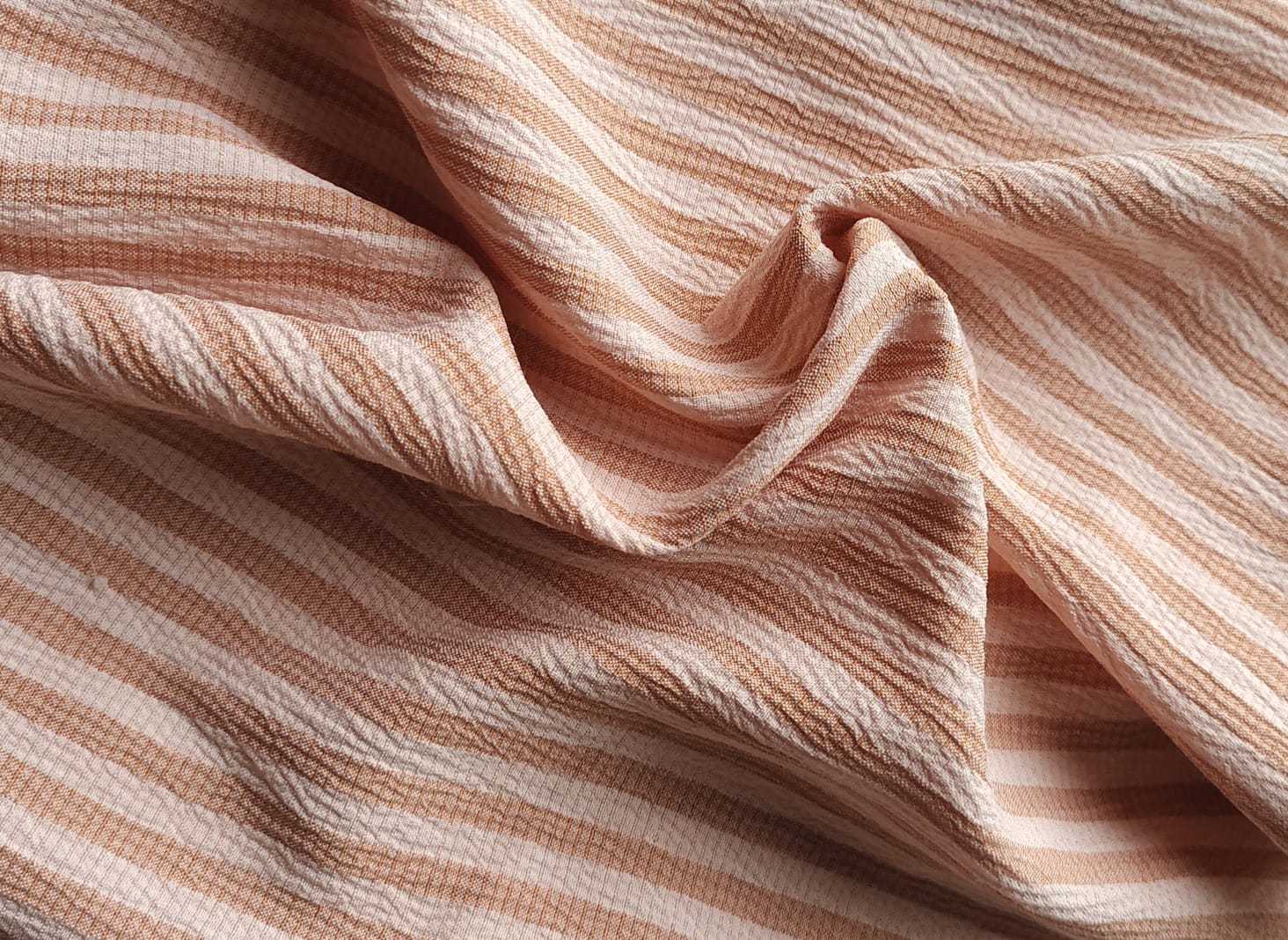 Close-up of soft, wrinkled pink cotton fabric displaying fine weave texture.