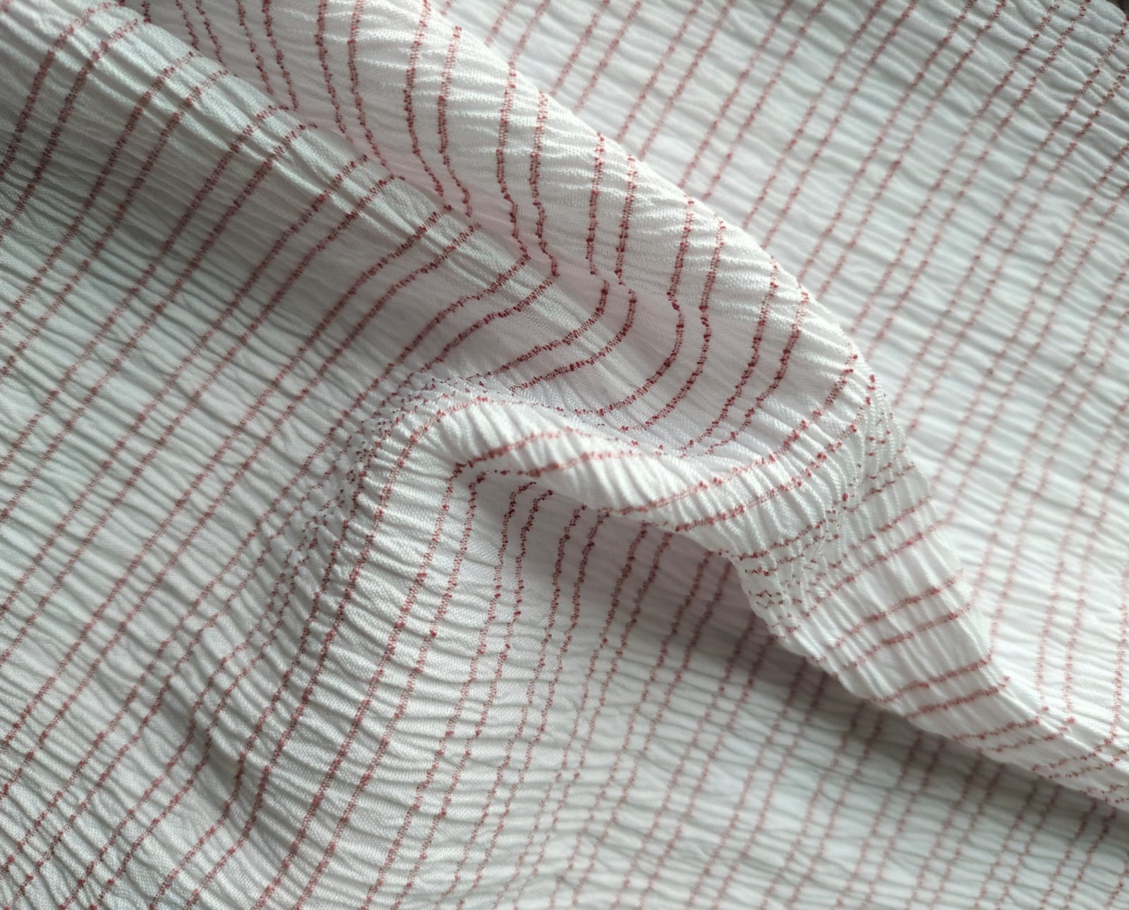 Close-up of soft, wrinkled pink cotton fabric displaying fine weave texture.