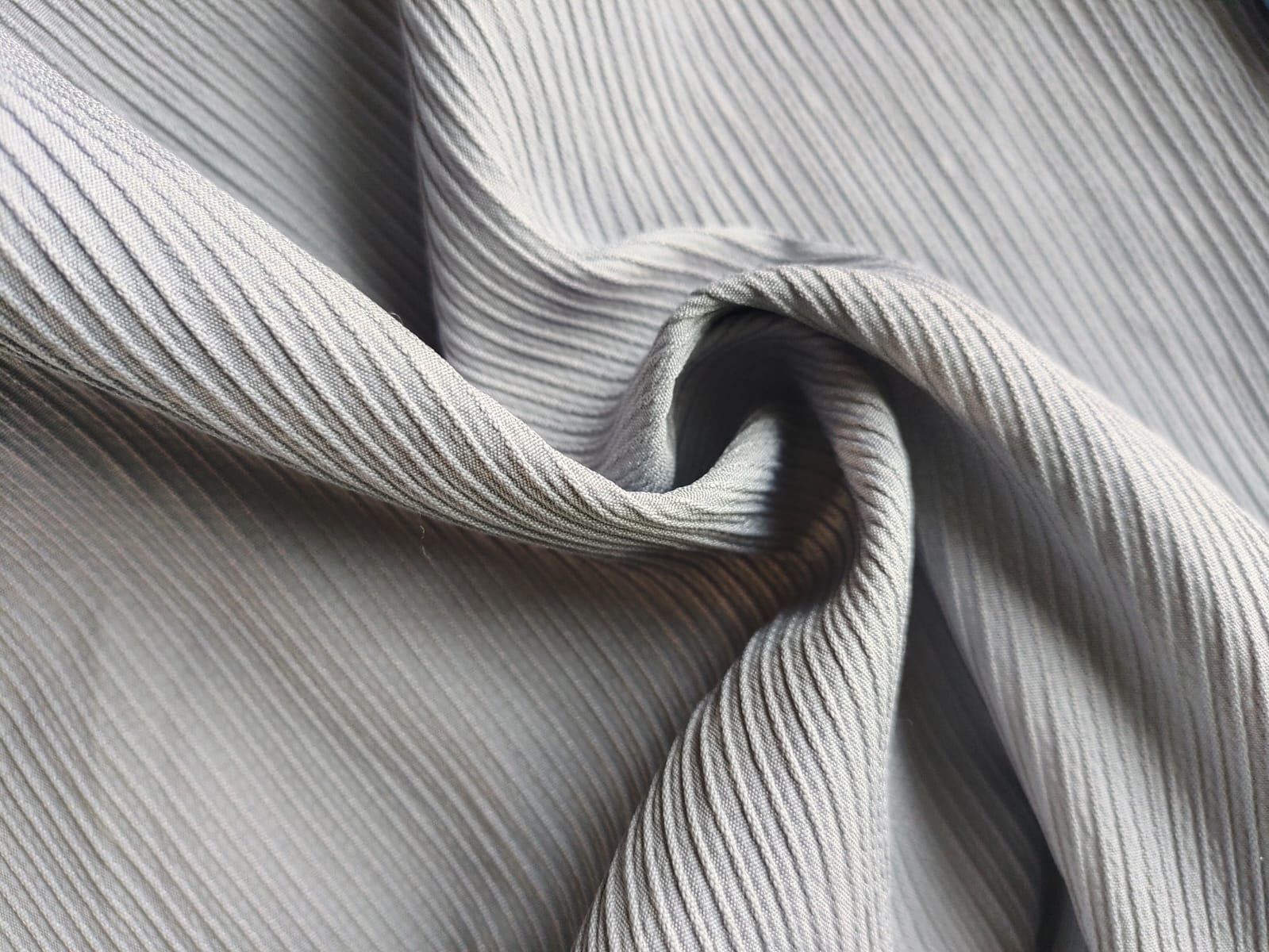 Close-up of soft, wrinkled pink cotton fabric displaying fine weave texture.