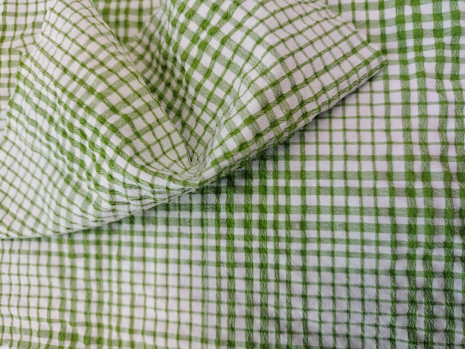 Close-up of soft, wrinkled pink cotton fabric displaying fine weave texture.