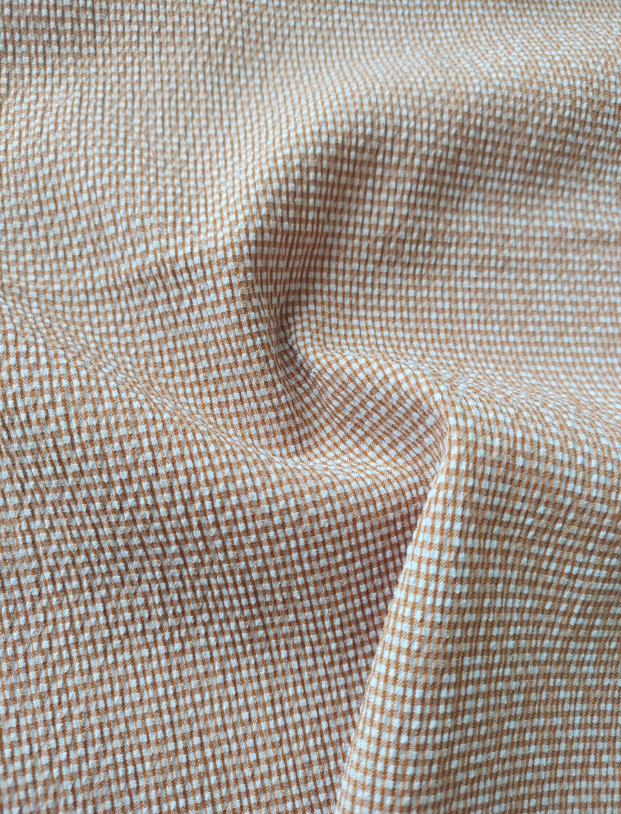 Close-up of soft, wrinkled pink cotton fabric displaying fine weave texture.