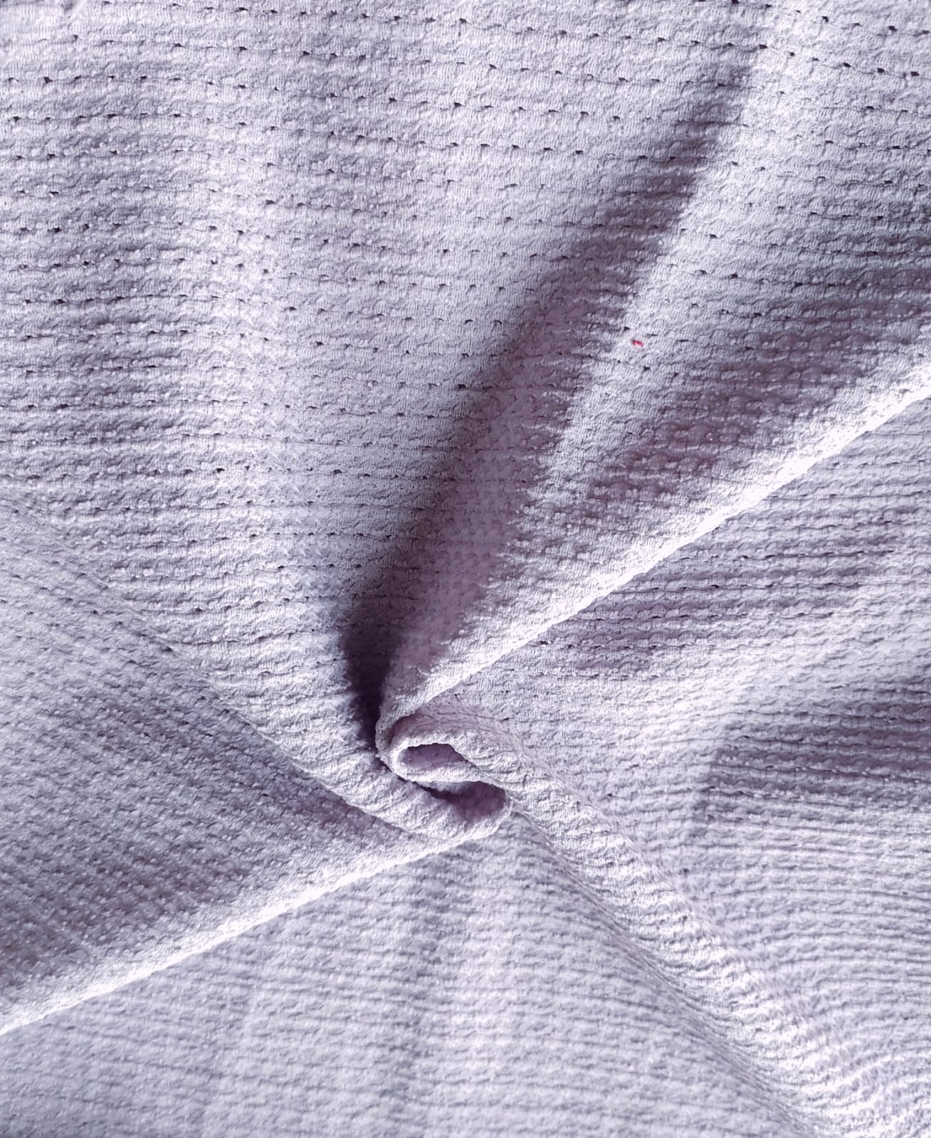 Close-up of soft, wrinkled pink cotton fabric displaying fine weave texture.