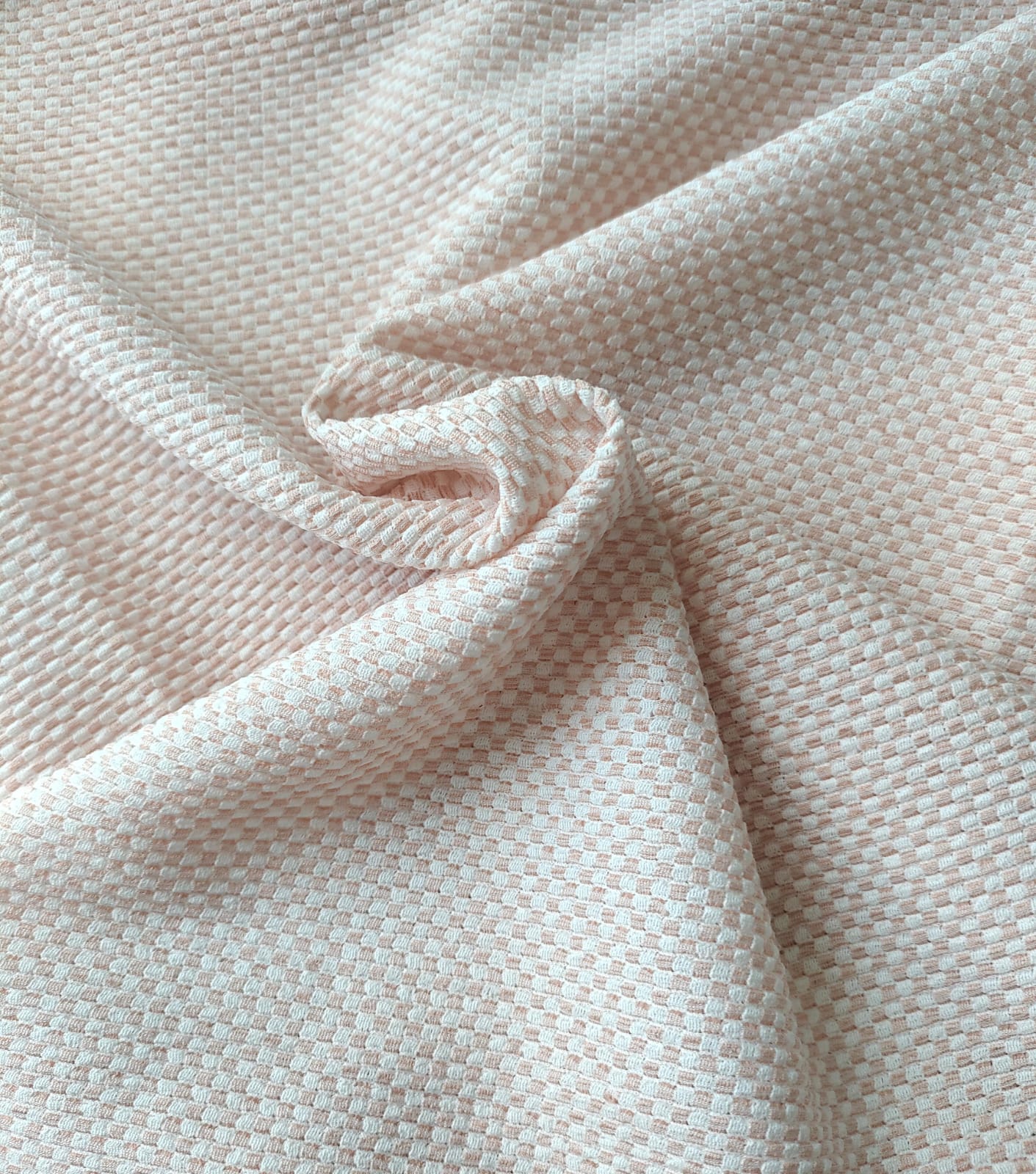Close-up of soft, wrinkled pink cotton fabric displaying fine weave texture.