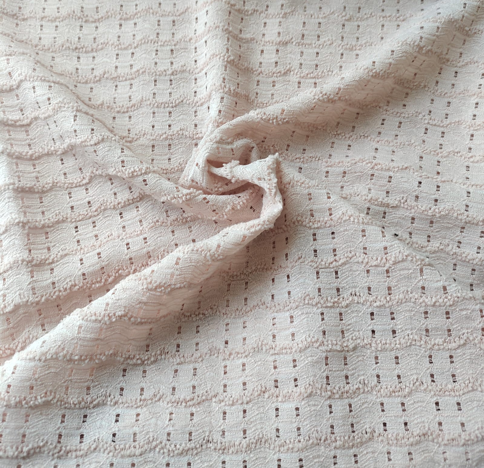 Close-up of soft, wrinkled pink cotton fabric displaying fine weave texture.