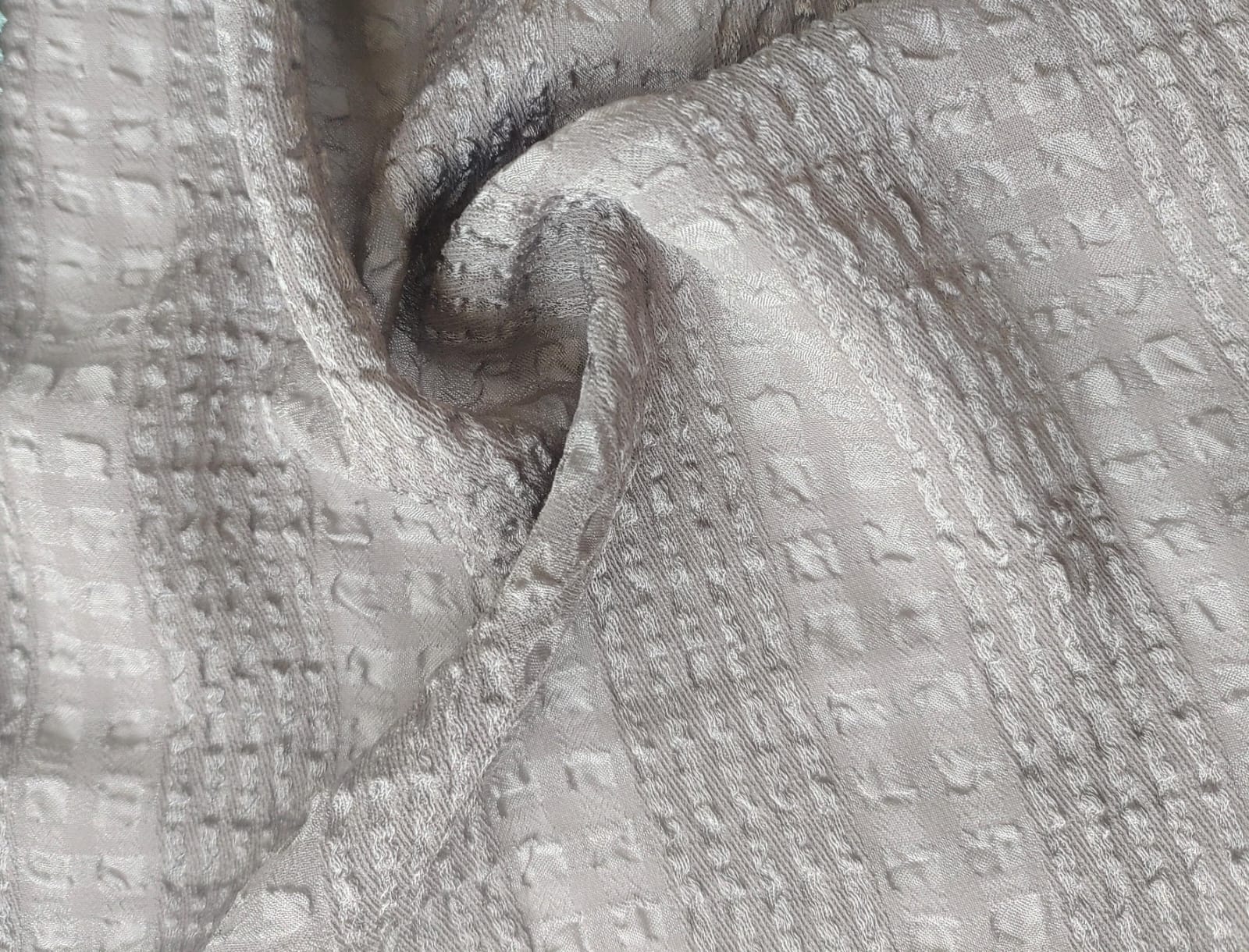 Close-up of soft, wrinkled pink cotton fabric displaying fine weave texture.