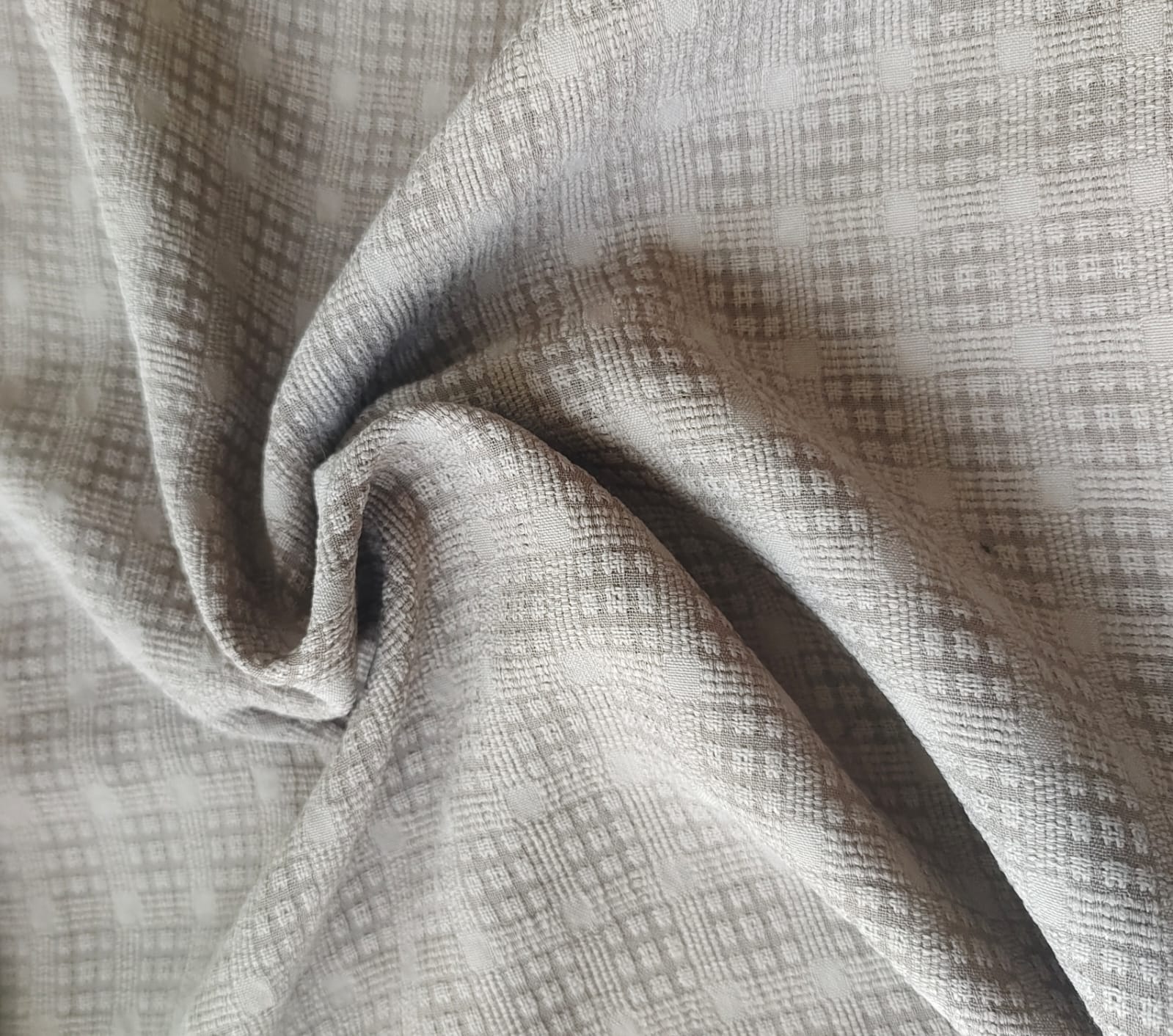 Close-up of soft, wrinkled pink cotton fabric displaying fine weave texture.