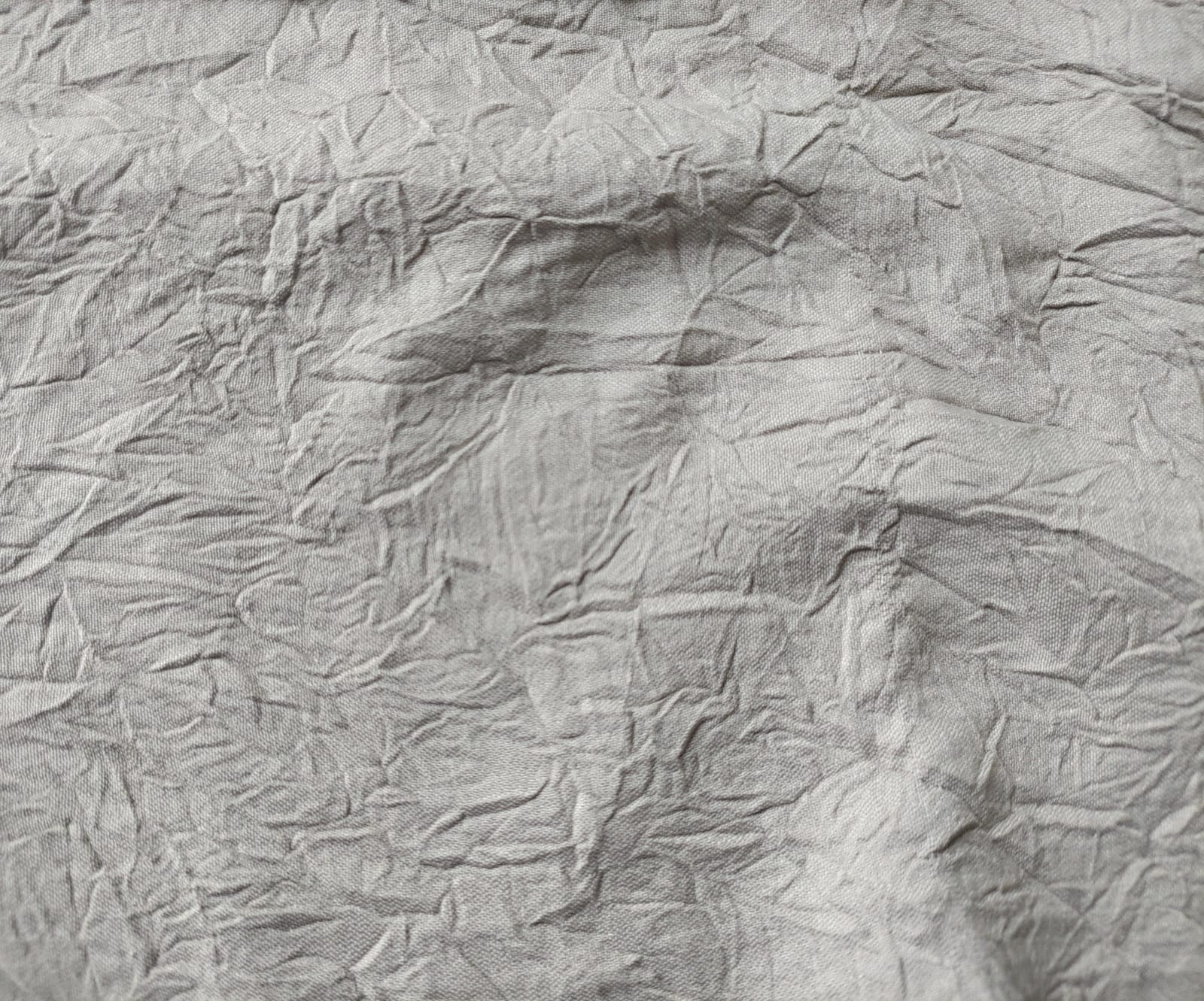 Close-up of soft, wrinkled pink cotton fabric displaying fine weave texture.