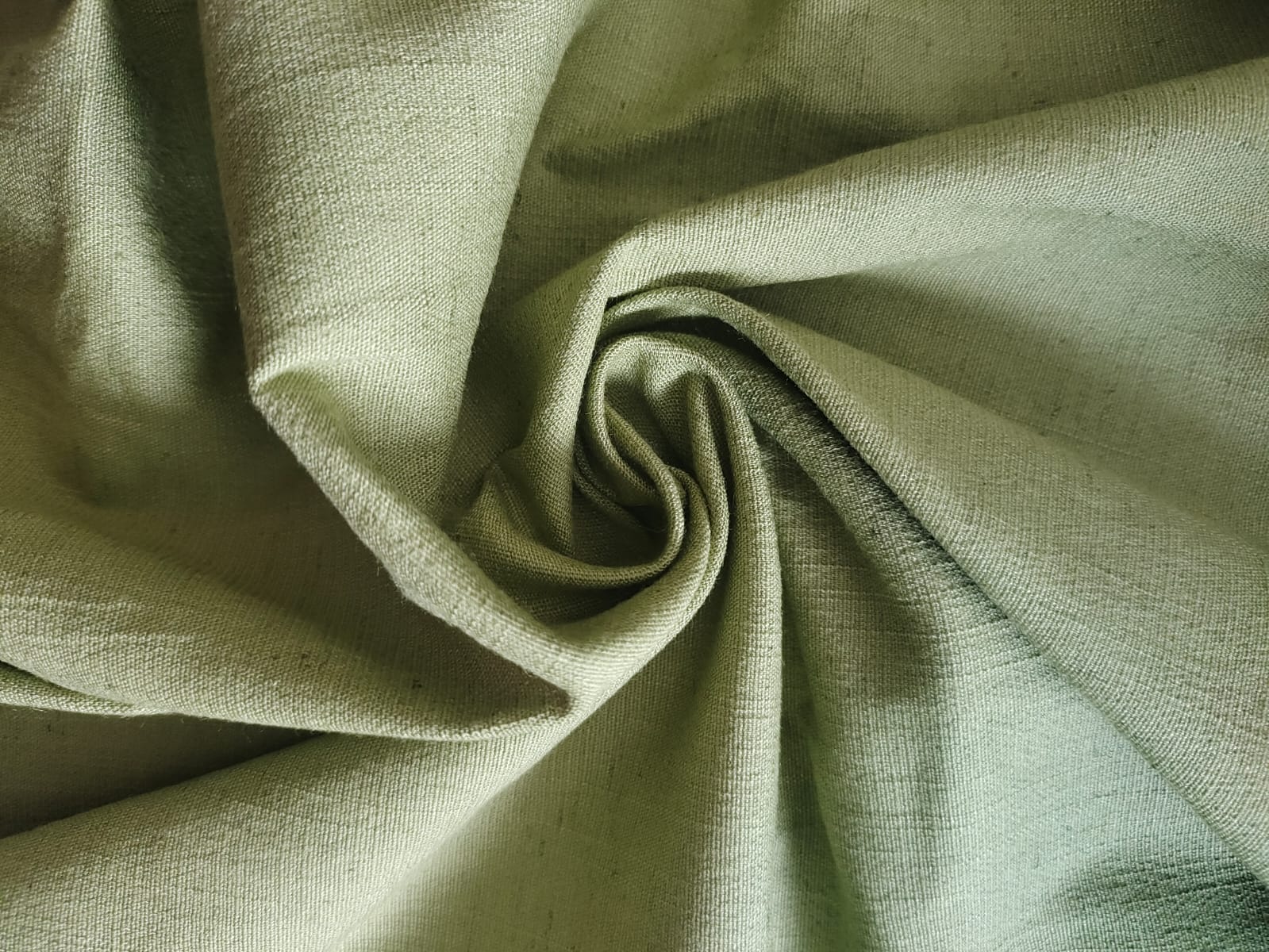 Close-up of soft, wrinkled pink cotton fabric displaying fine weave texture.