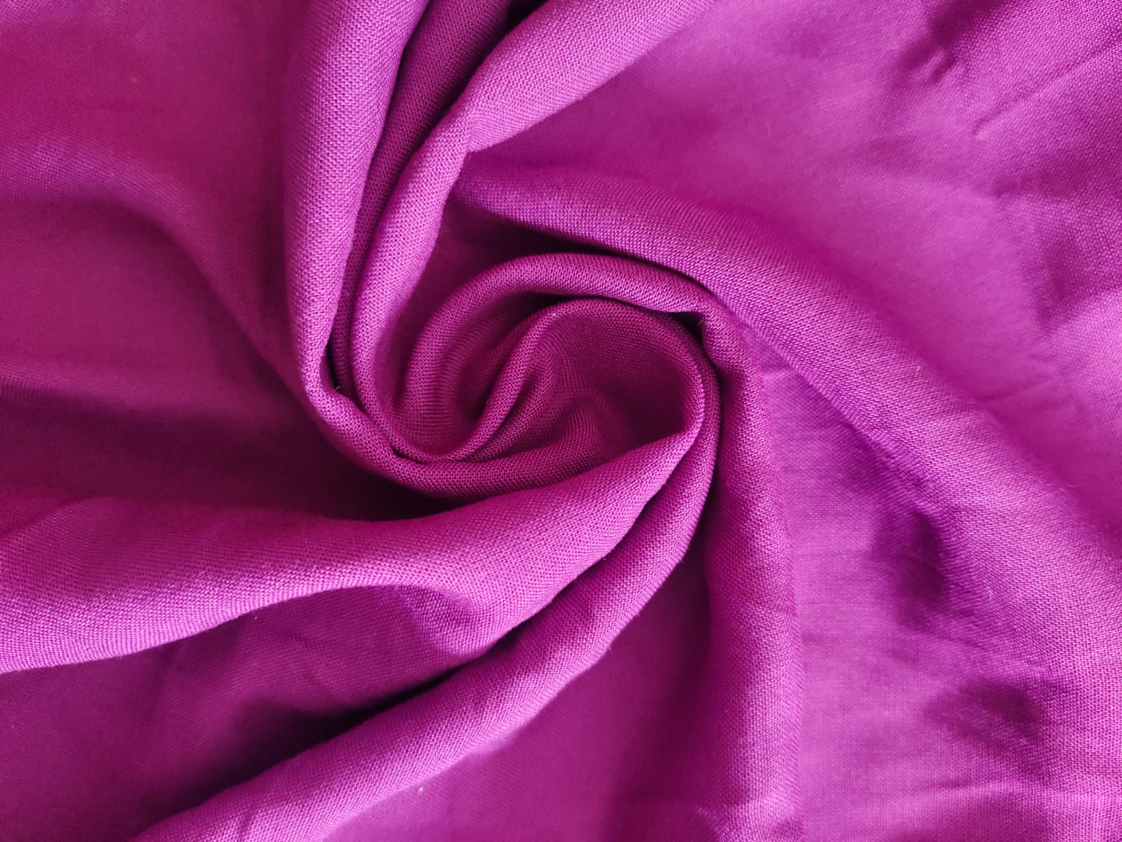 Close-up of soft, wrinkled pink cotton fabric displaying fine weave texture.