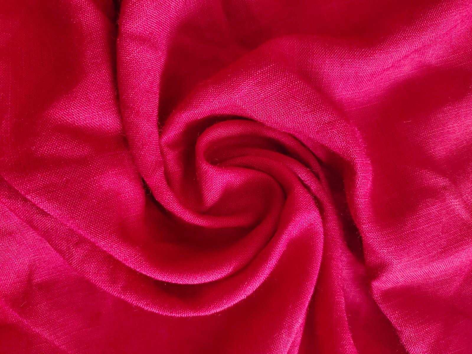 Close-up of soft, wrinkled pink cotton fabric displaying fine weave texture.