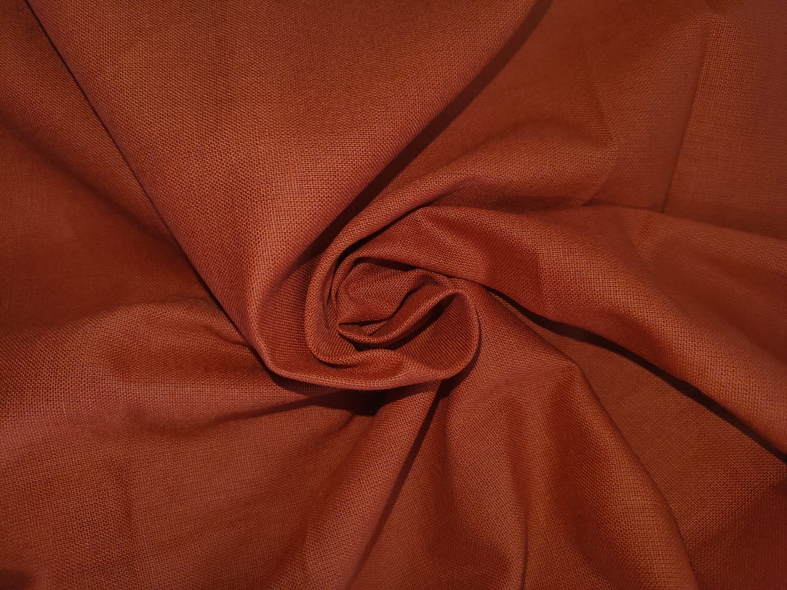 Close-up of soft, wrinkled pink cotton fabric displaying fine weave texture.