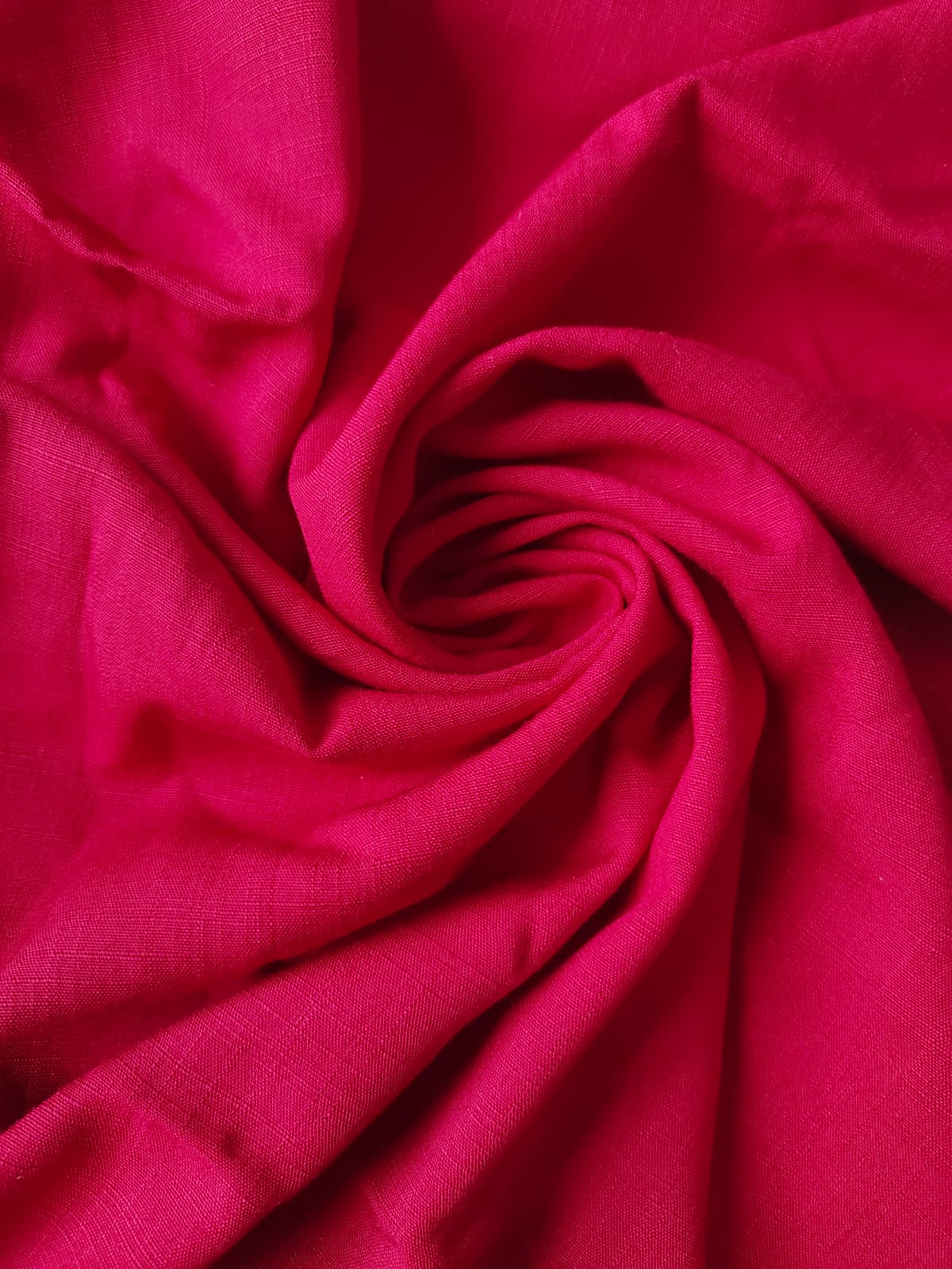 Close-up of soft, wrinkled pink cotton fabric displaying fine weave texture.