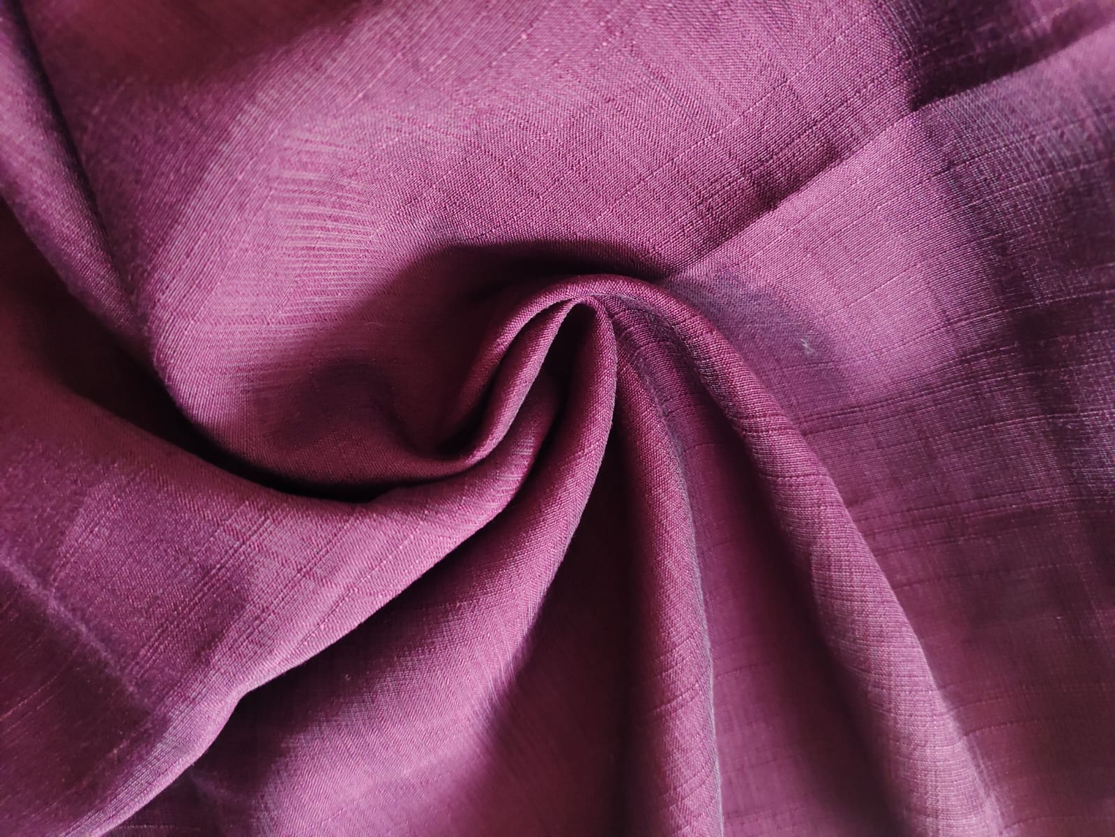 Close-up of soft, wrinkled pink cotton fabric displaying fine weave texture.
