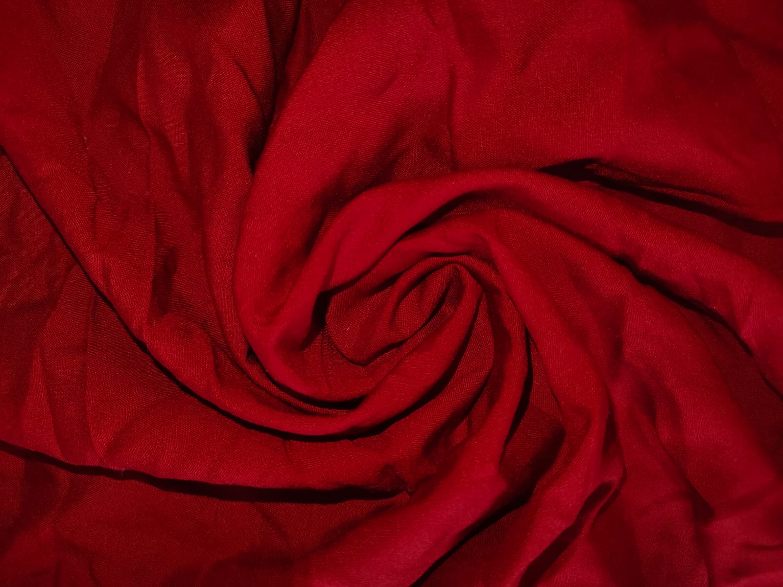 Close-up of soft, wrinkled pink cotton fabric displaying fine weave texture.