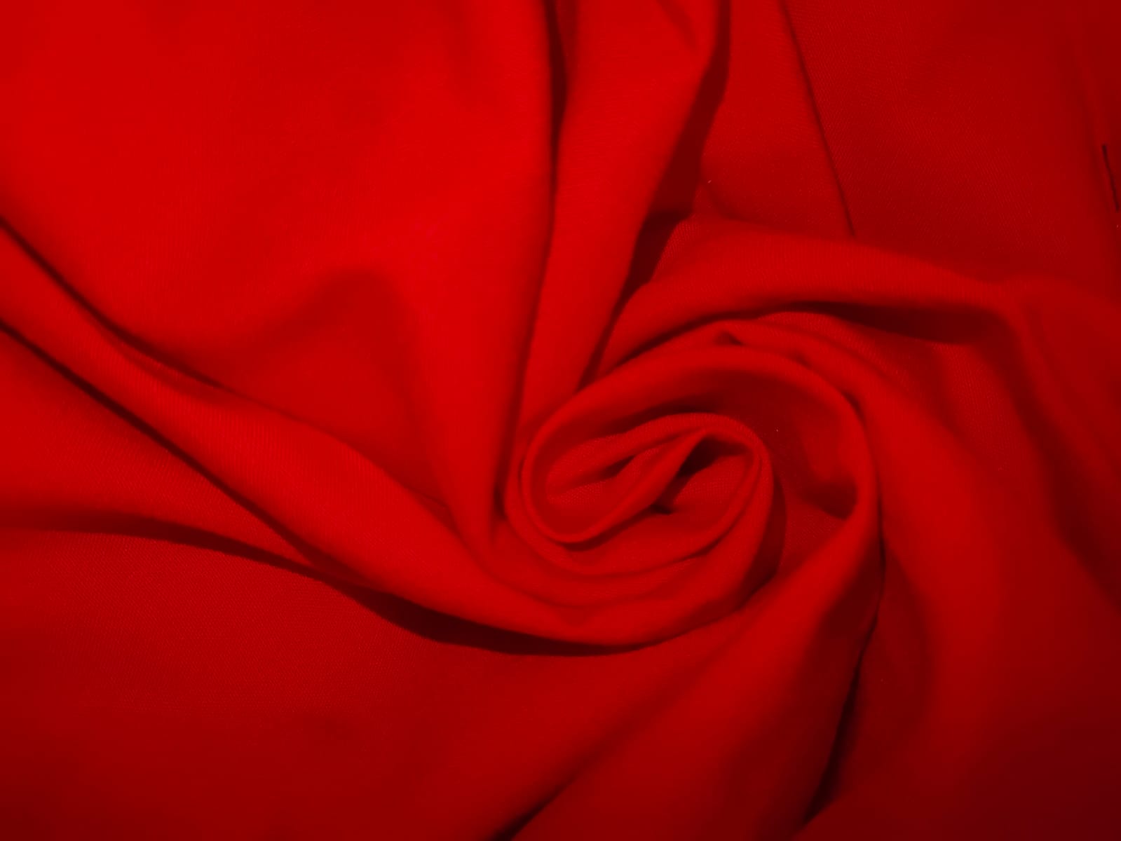 Close-up of soft, wrinkled pink cotton fabric displaying fine weave texture.