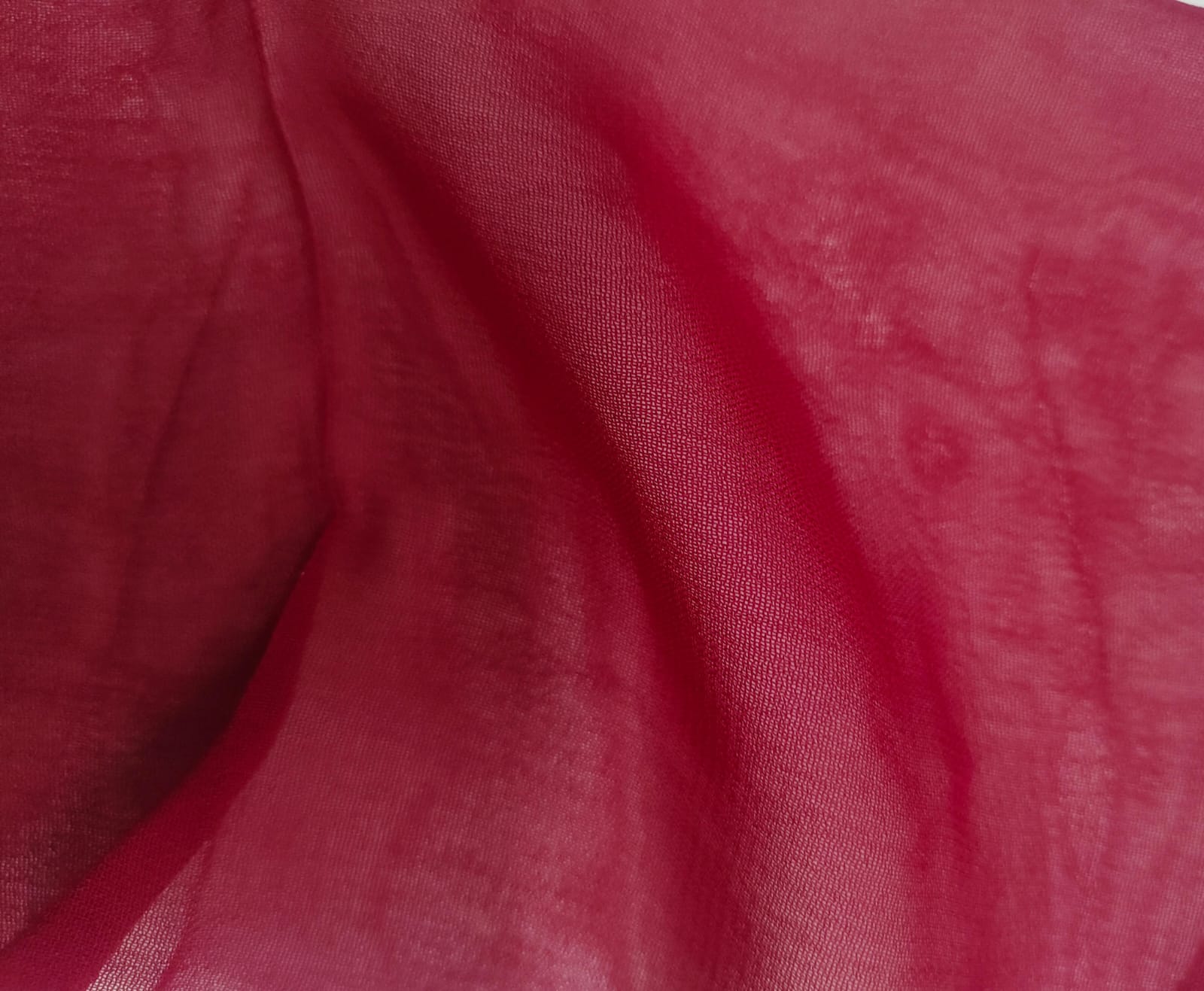 Close-up of soft, wrinkled pink cotton fabric displaying fine weave texture.